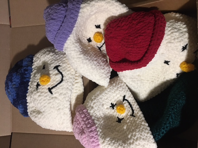 A group of winter hats crocheted to look like snowmen wearing hats