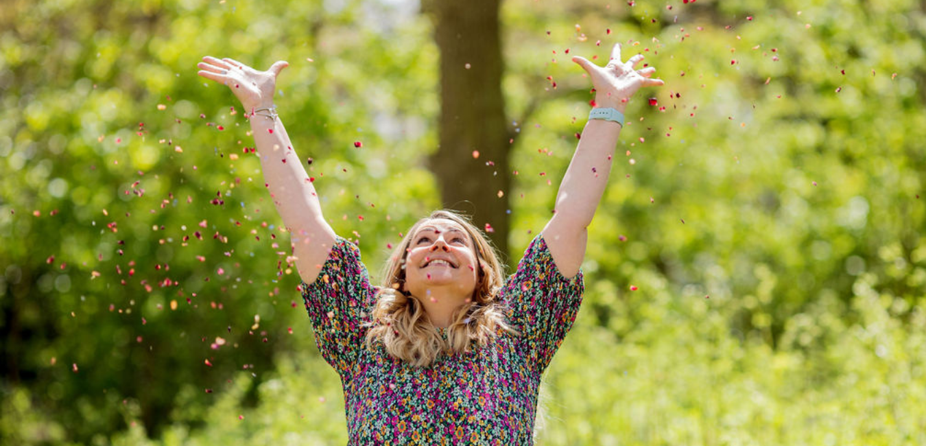 Emma from Los Social surrounded by sticky notes on a white wall, with hands open in a welcoming expression