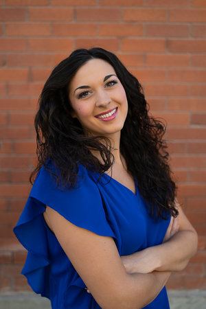 Kirstyn smiling, standing in front of a brick wall