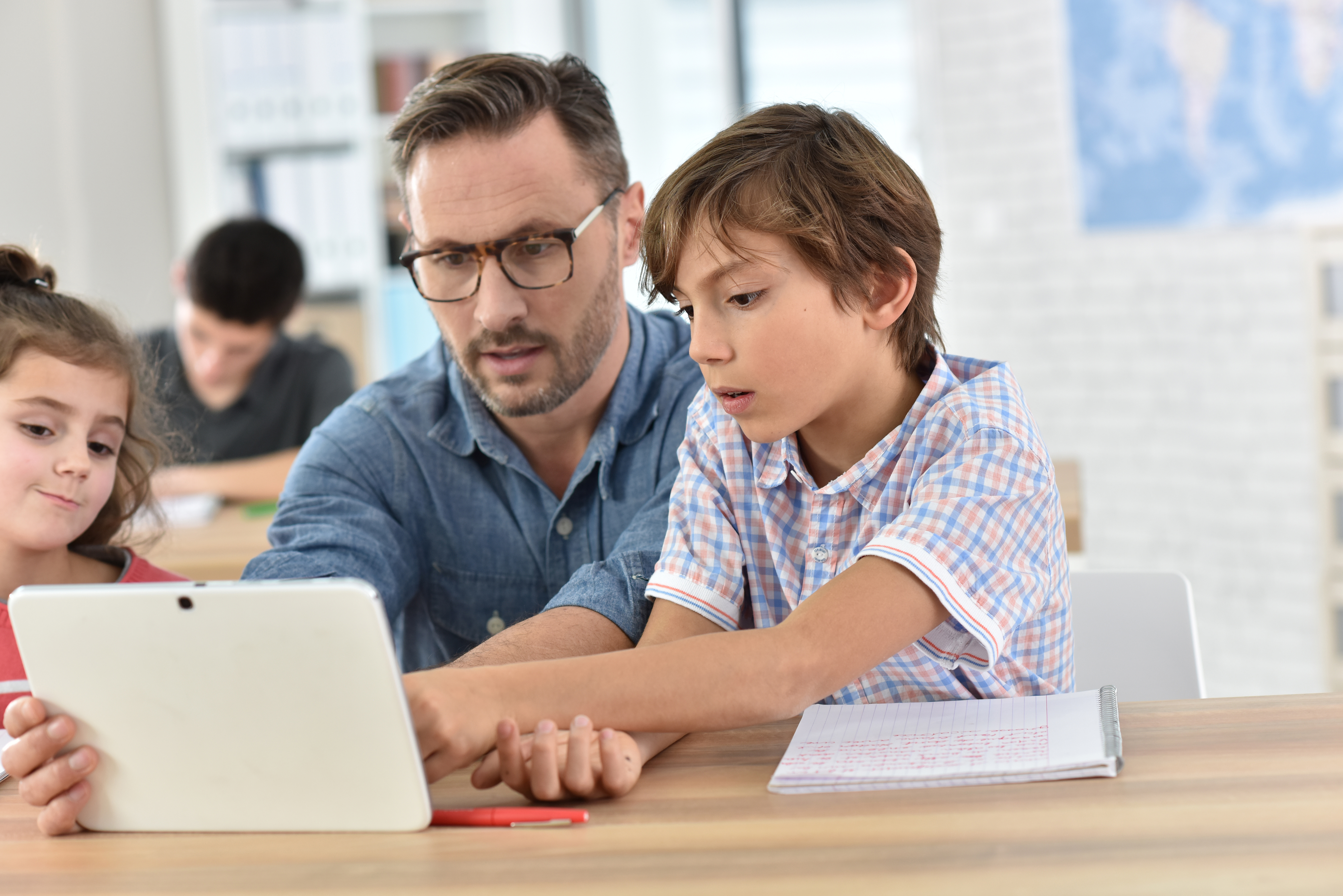 Teacher with 2 young students using a tablet