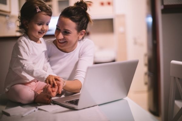 mother and toddler in front of laptop smiling