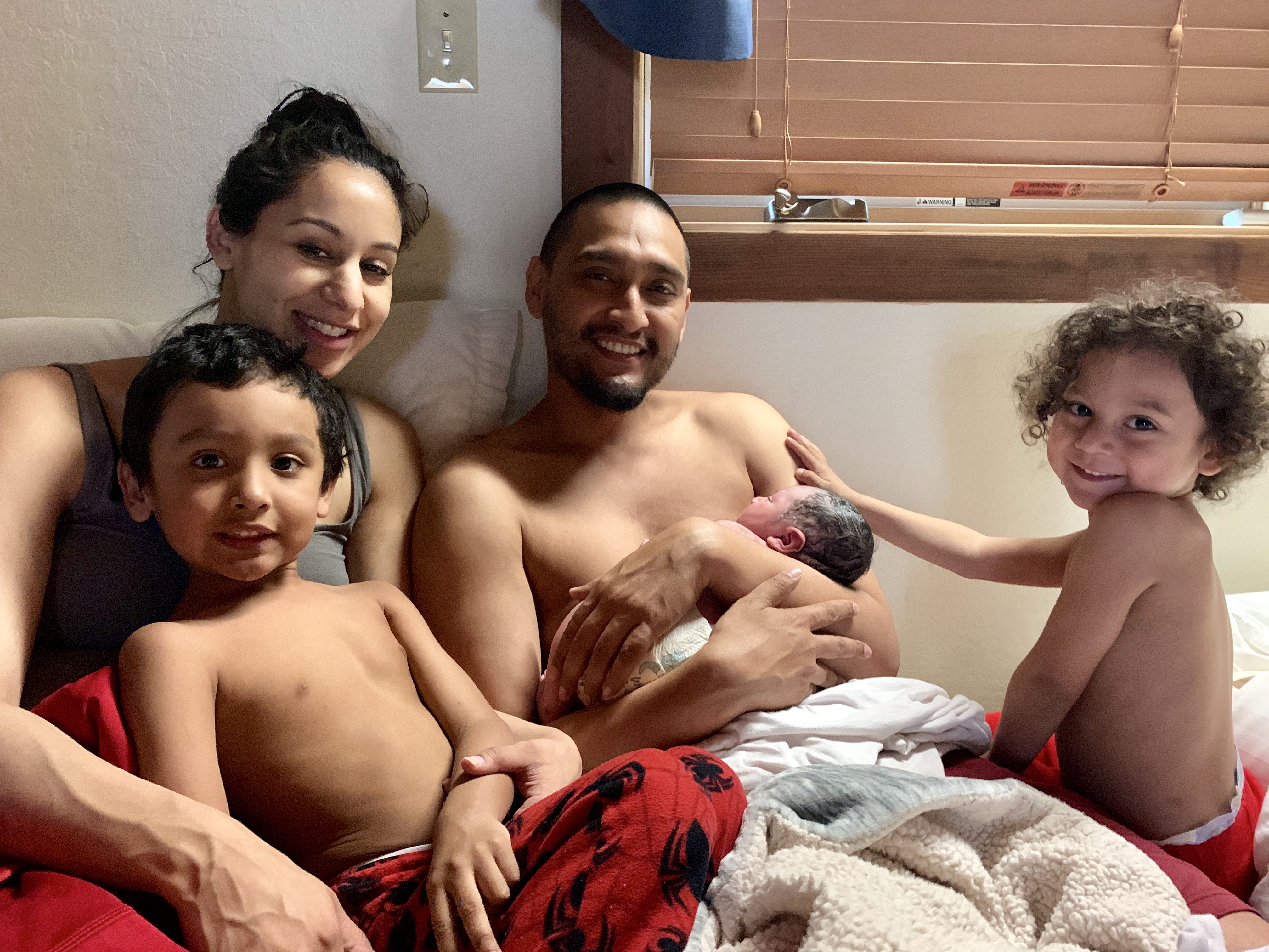 A family of five in bed together after their new baby was born