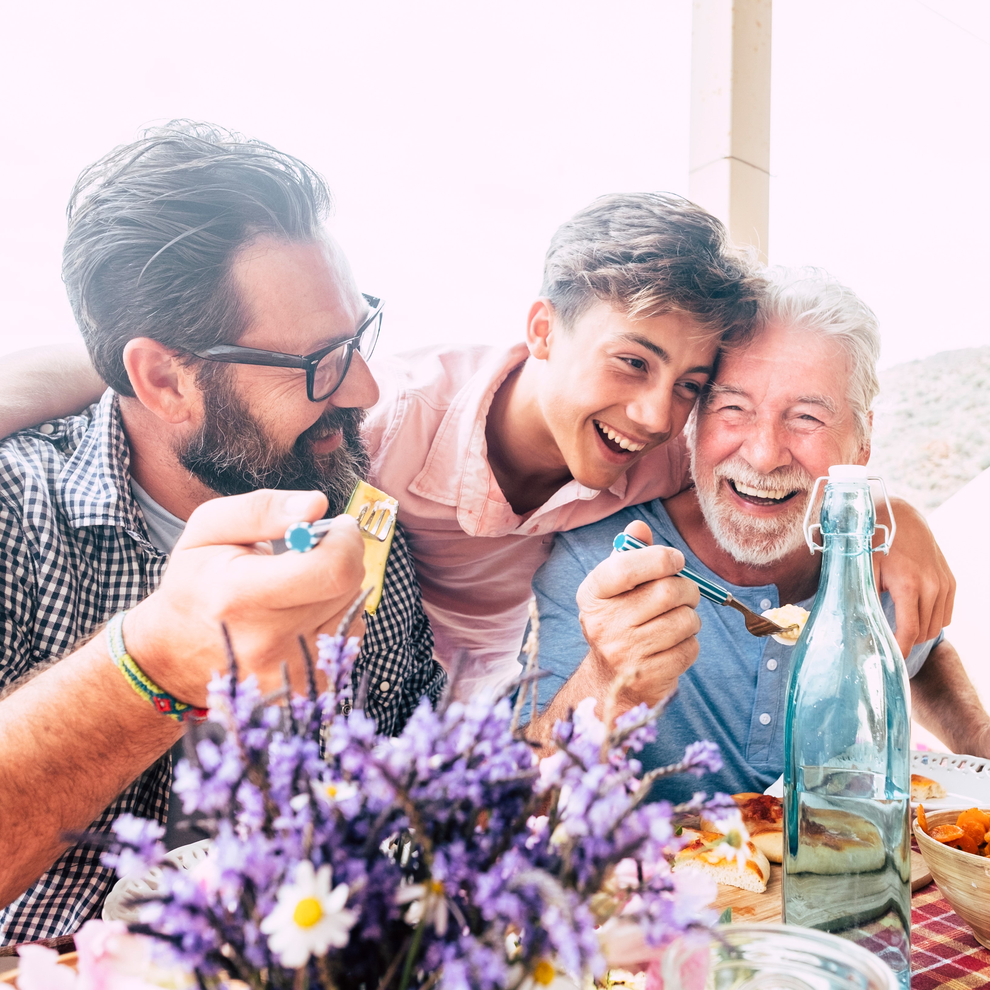 Grandpa, dad, and son laughing together over a meal