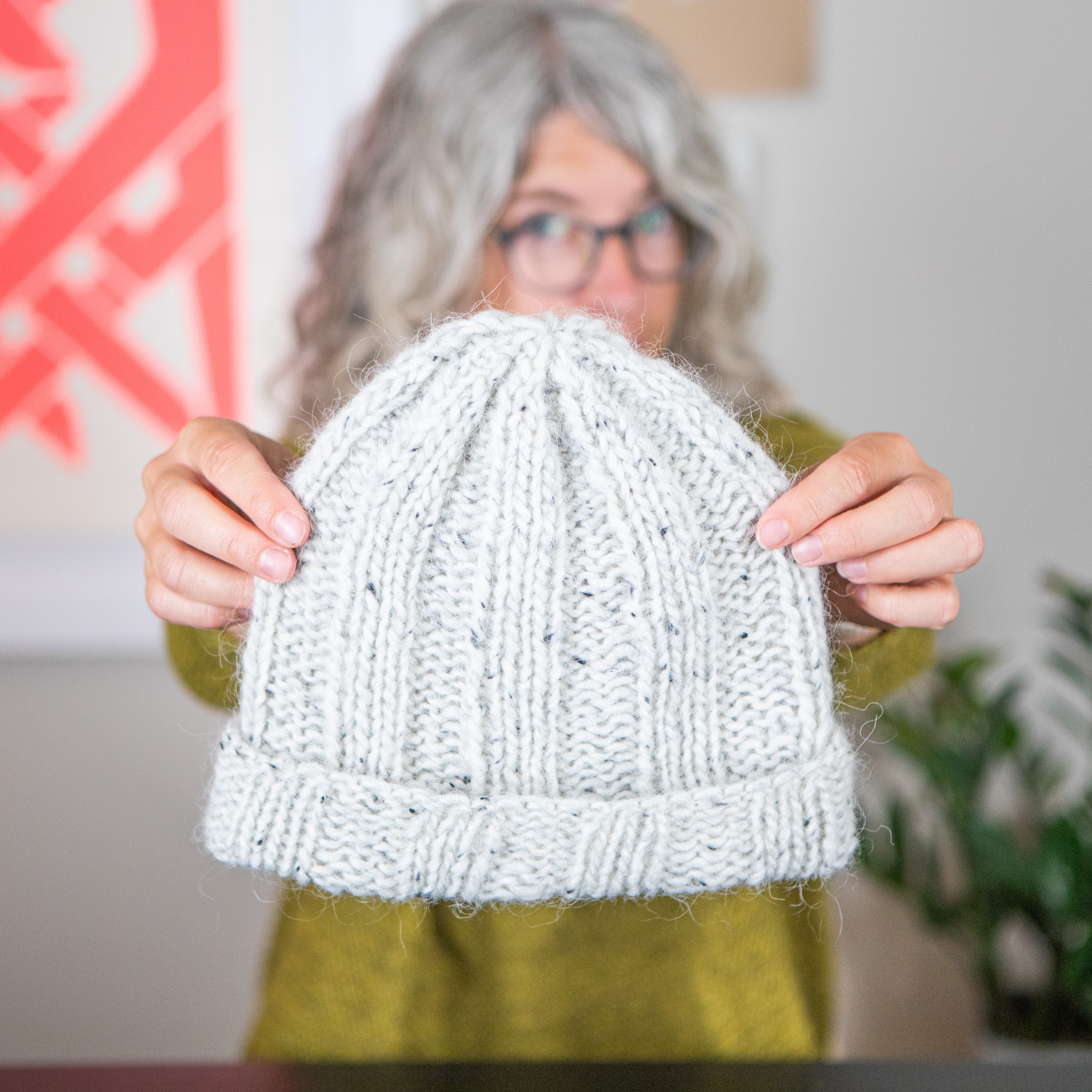 Jaime holding a knit hat to the camera