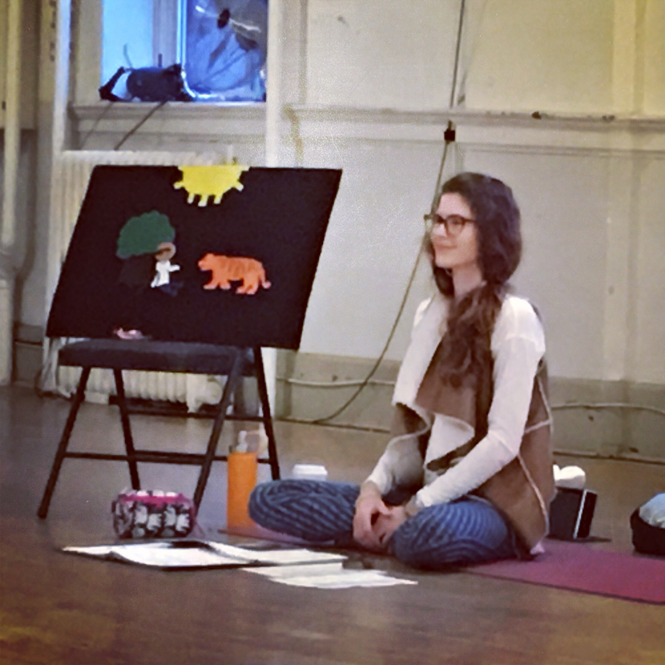 A woman in a seated yoga pose with a painting on the left side.