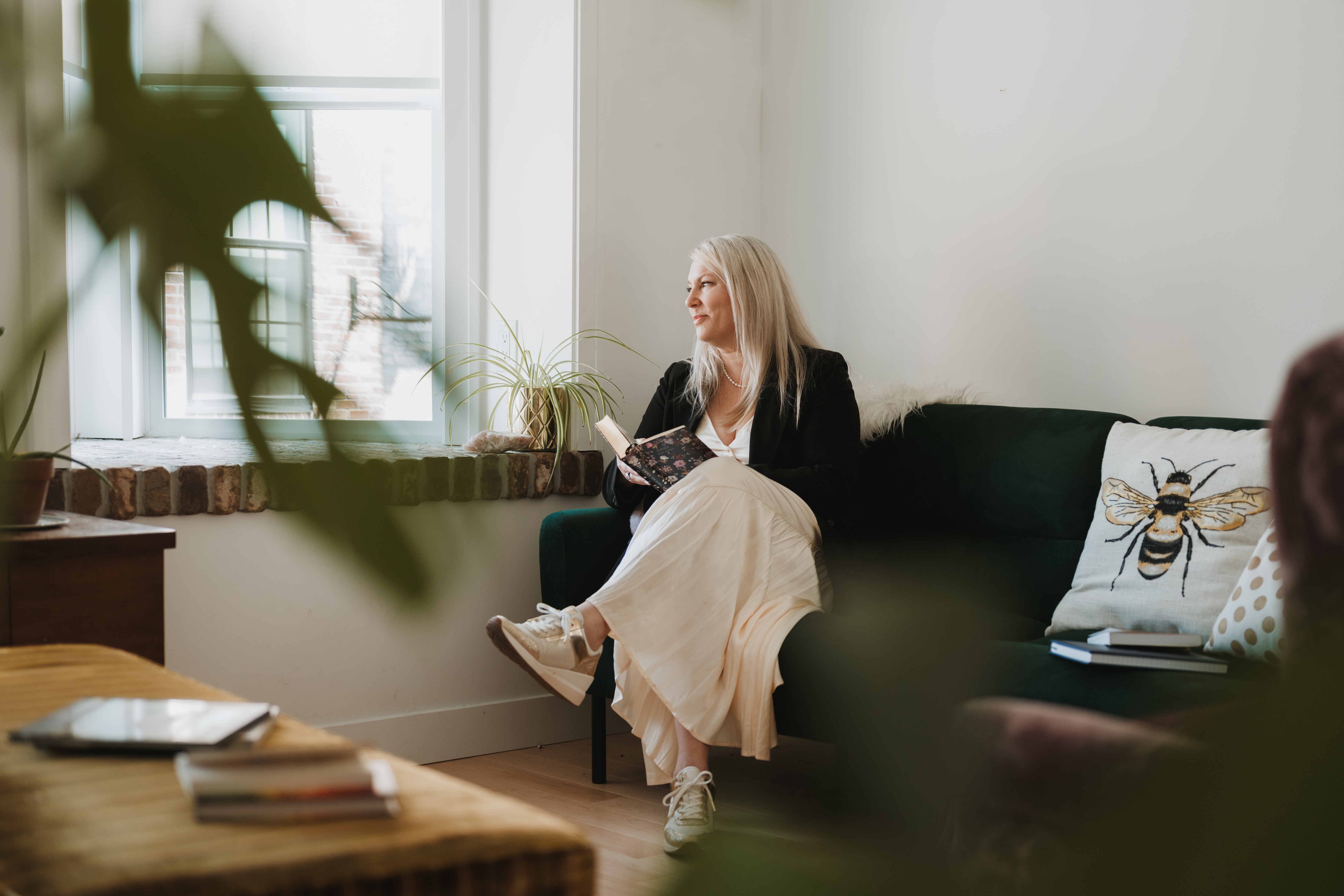 woman sitting happy looking out the window with a book in her hand