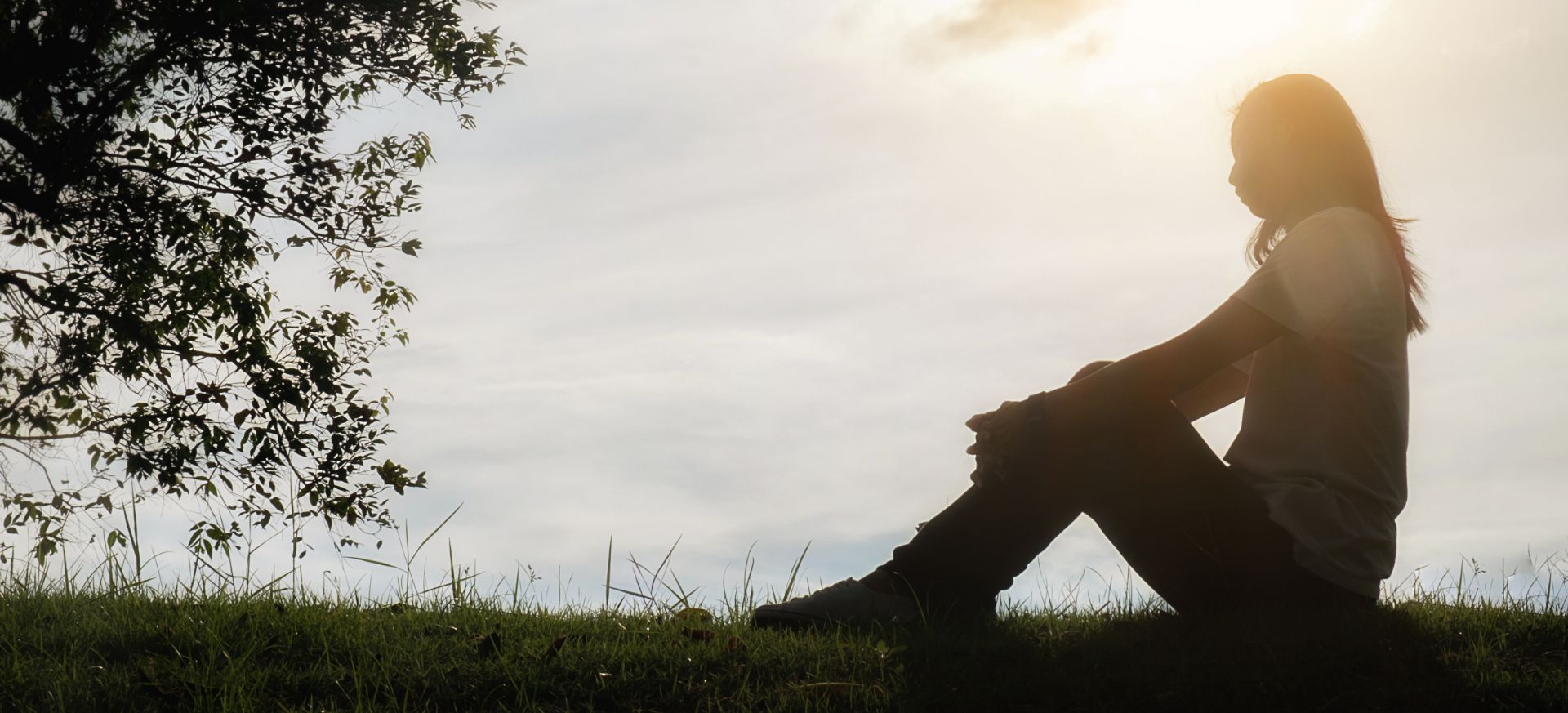 Girl sitting in the grass in the evening