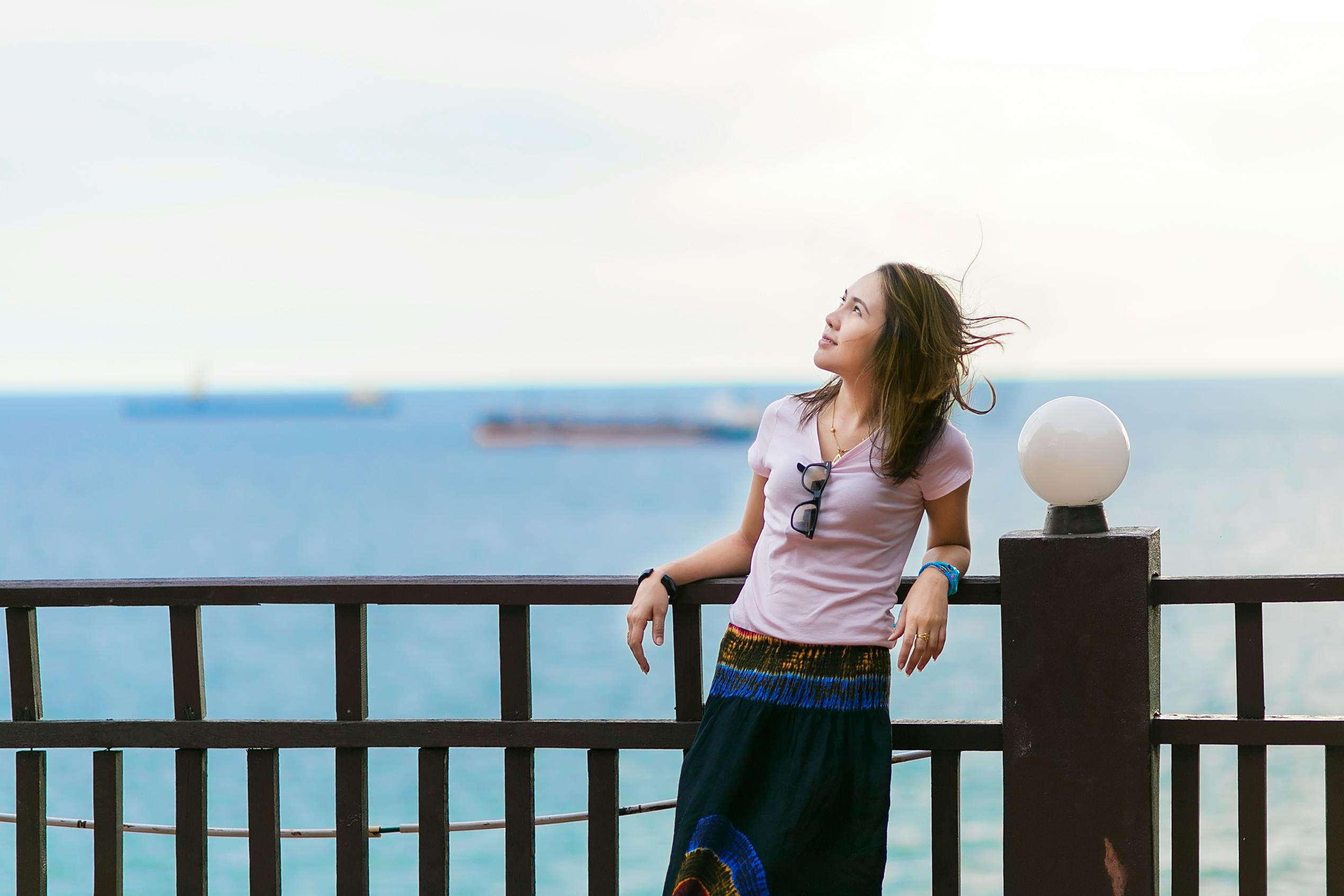 woman looking up to the sky in front of water and boats