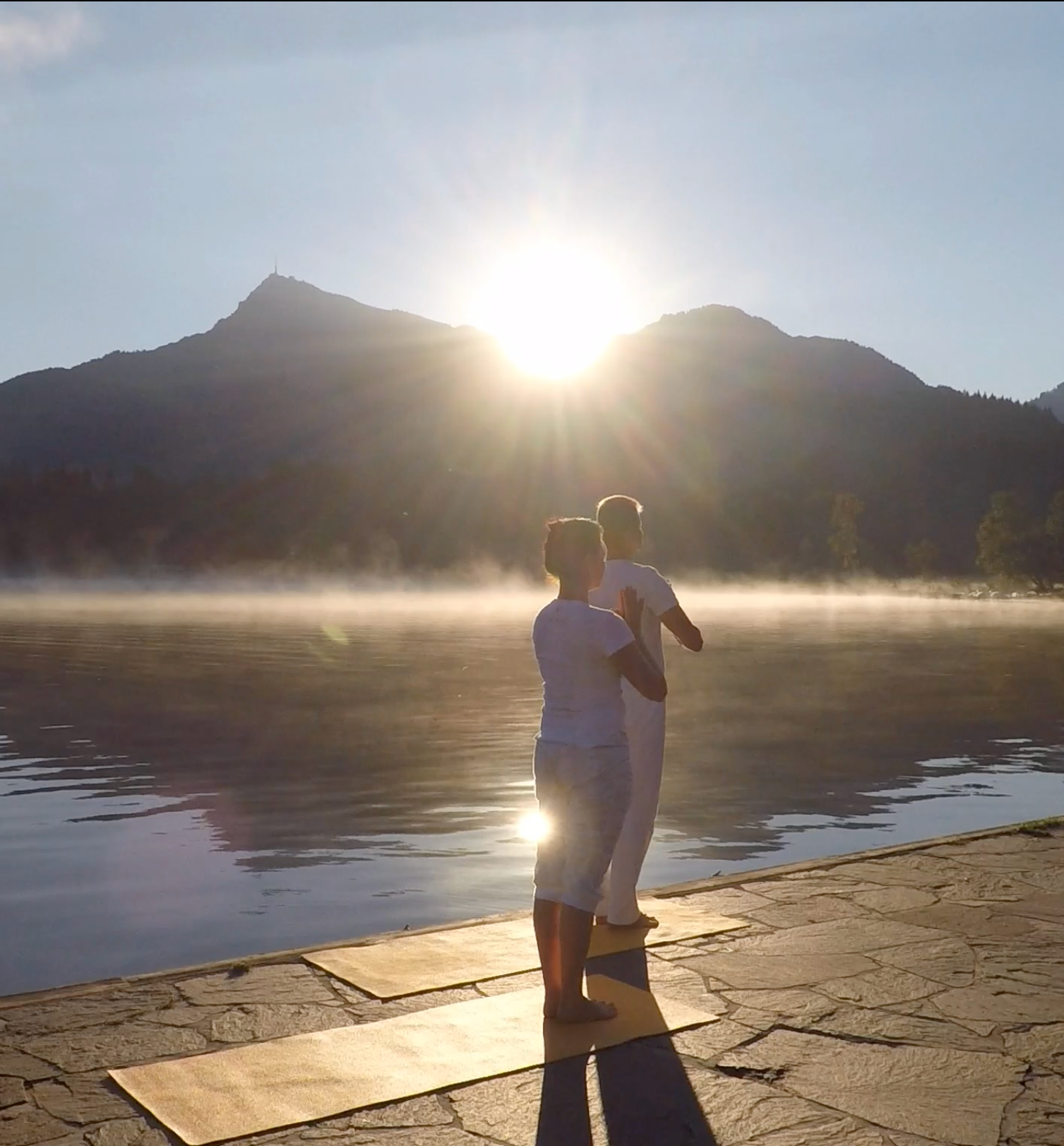 two people doing surya namaskar facing the sun