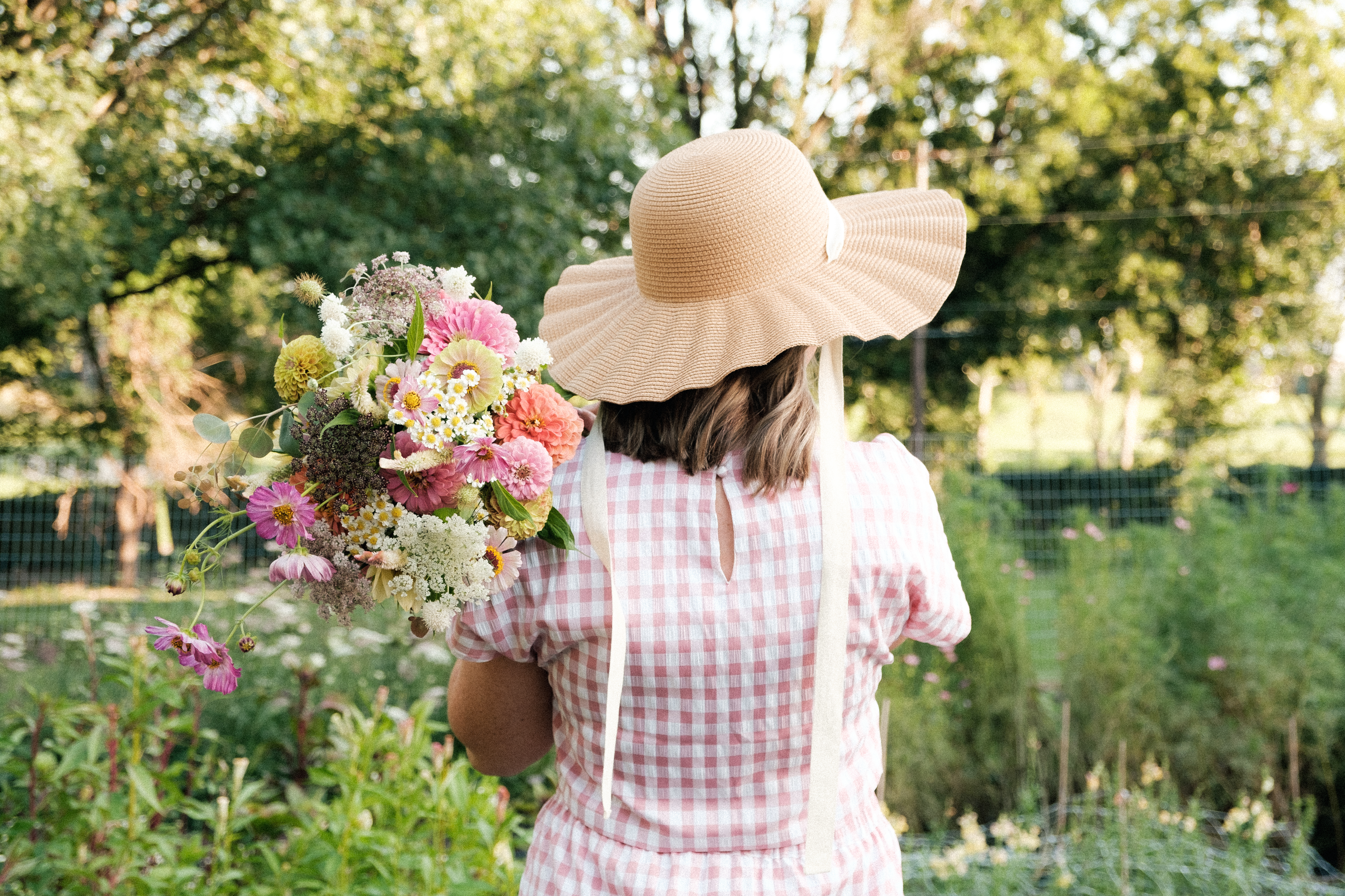 woman in garden holding bouquet of cut flowers