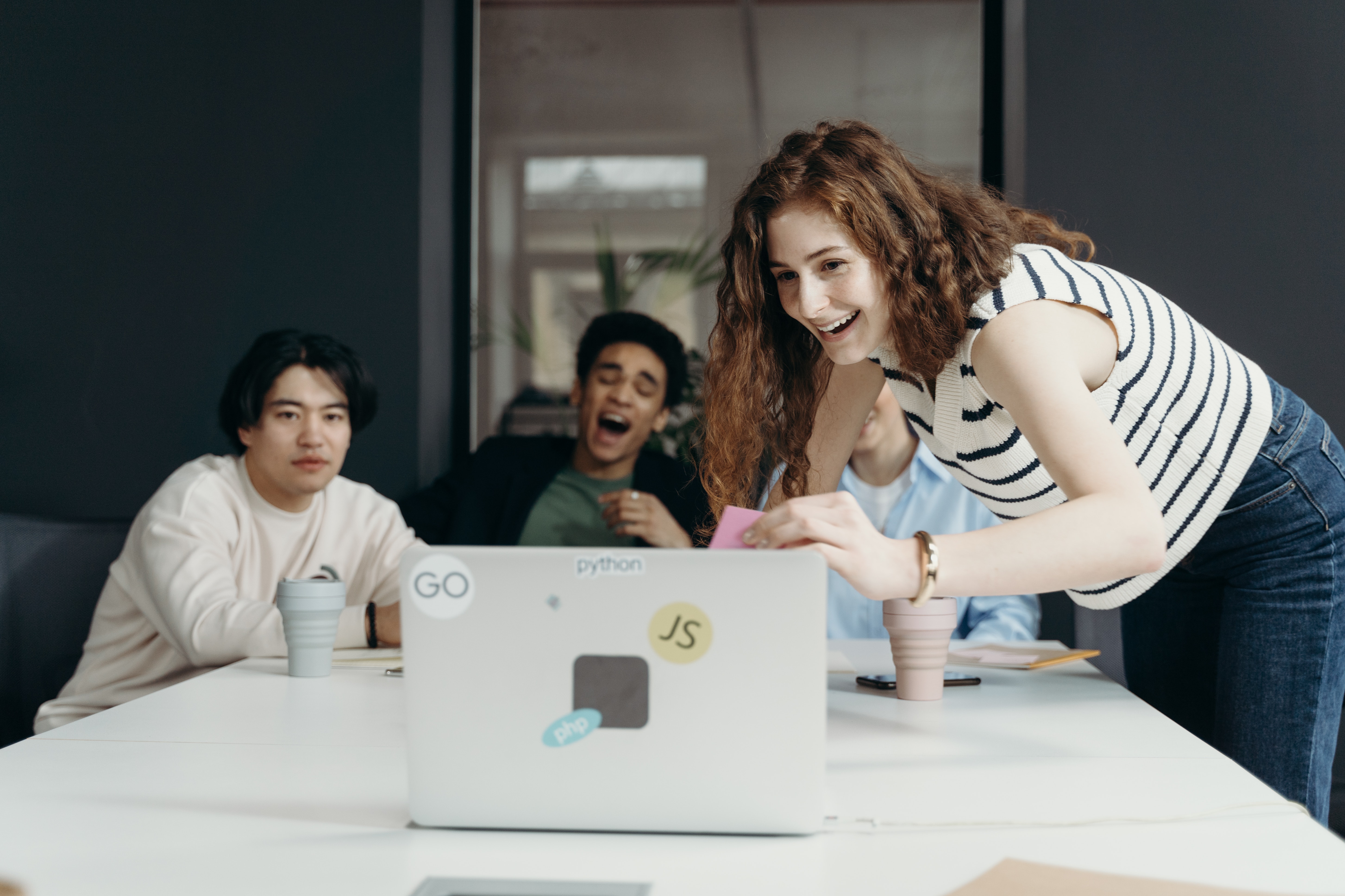 Team huddles around a computer, smiling.