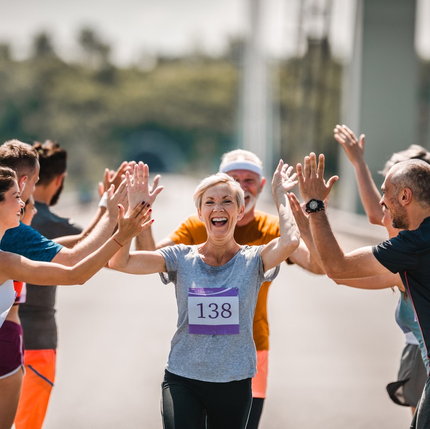 Retired woman finishing a race, friends cheering