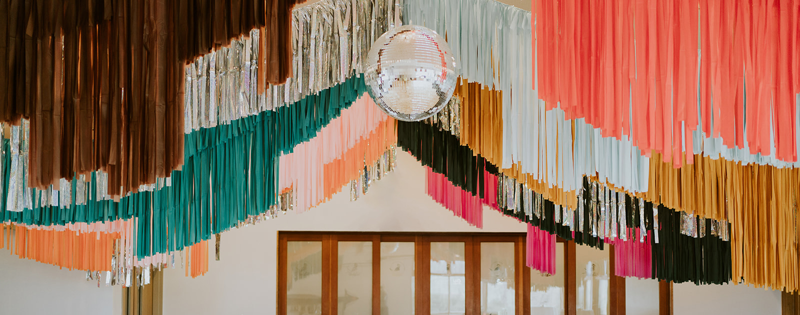 Disco ball in front of a colorful fringe banner