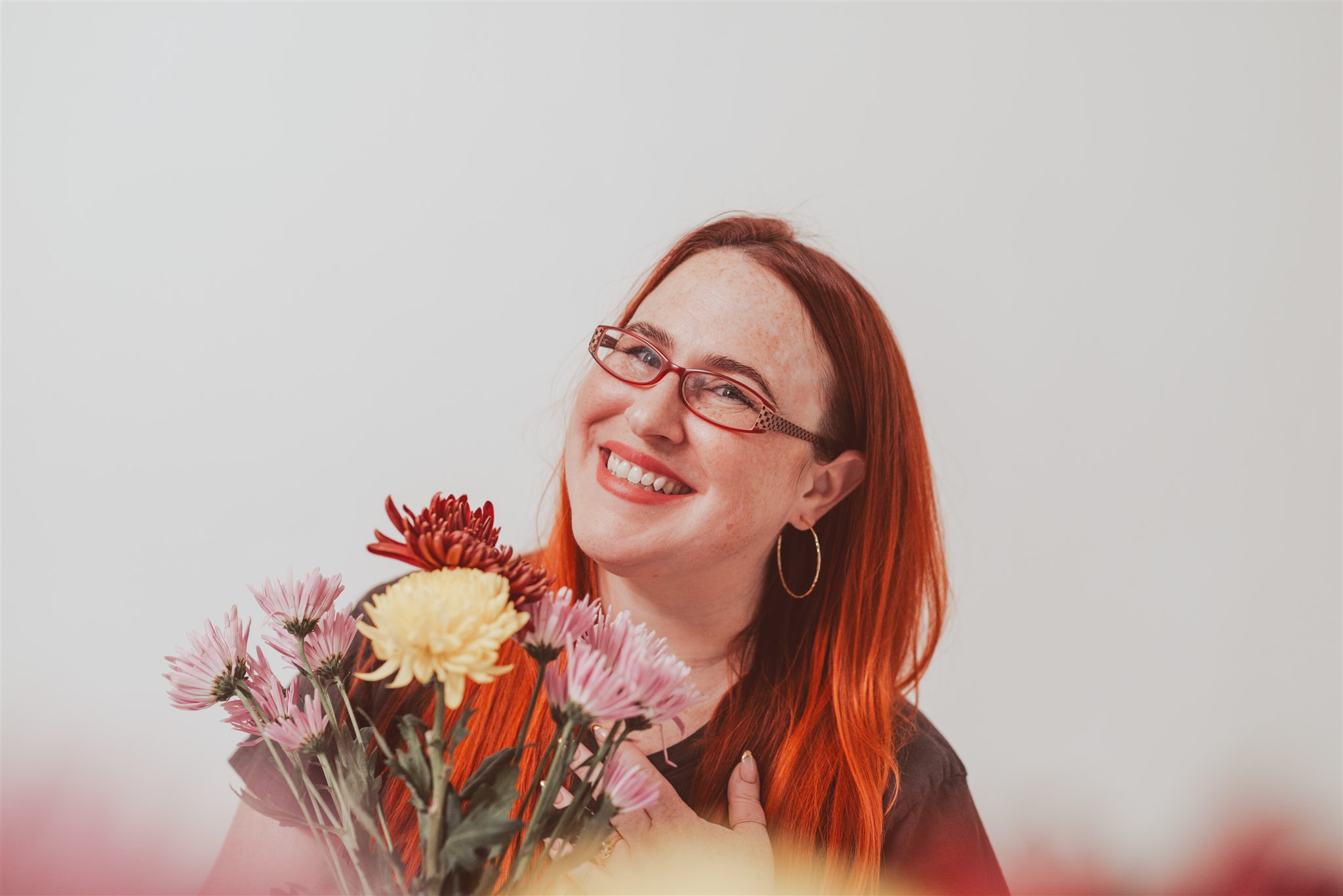 photo of Brynn smiling while holding long stem wild flowers