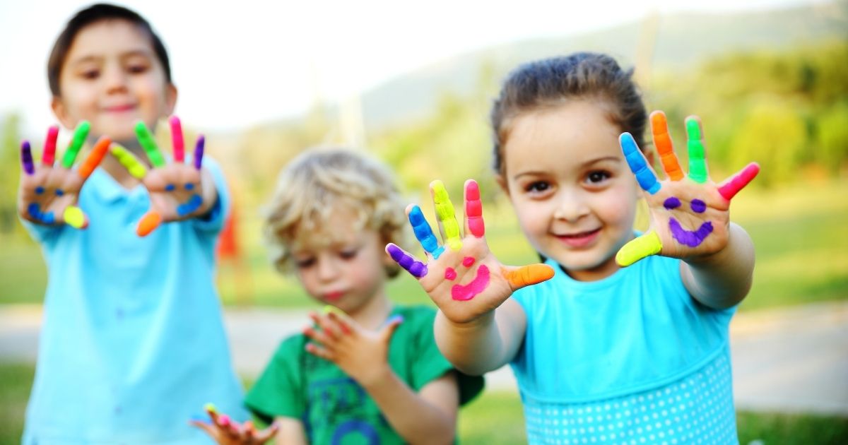 the picture is of three children showing their hands that are covered in various colors of finger paint.