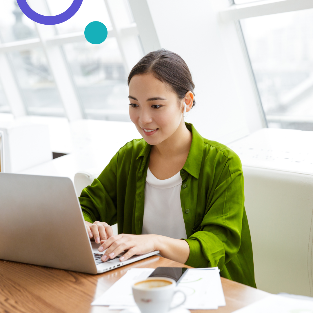 Woman seated on bench working on a laptop