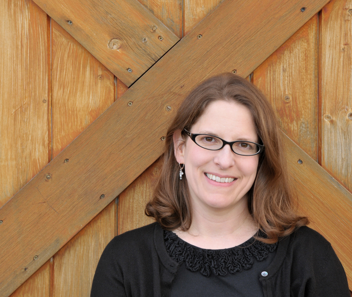 a white women with glasses and shoulder length brown hair smiles at the camera