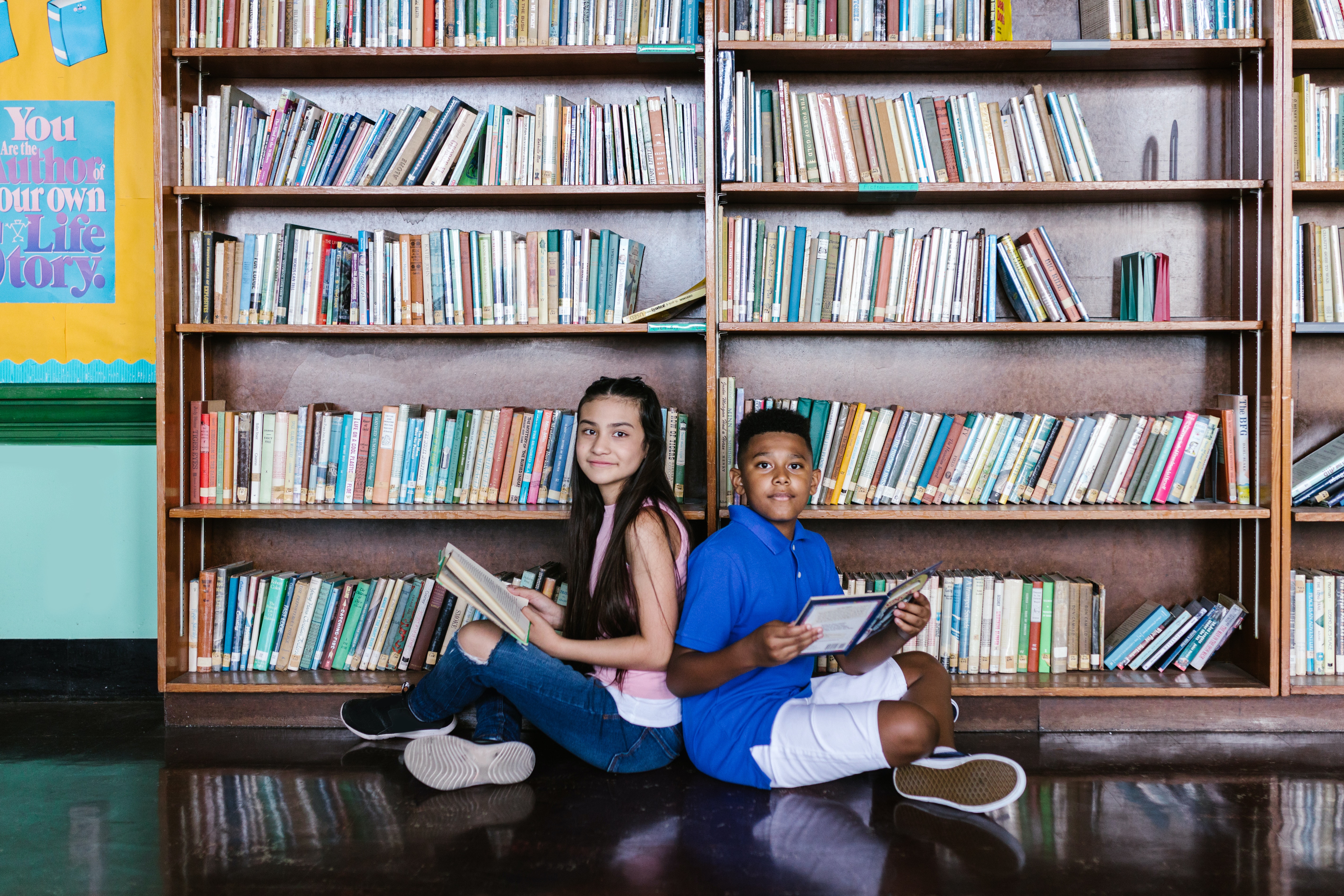 two students sitting in front of bookcases