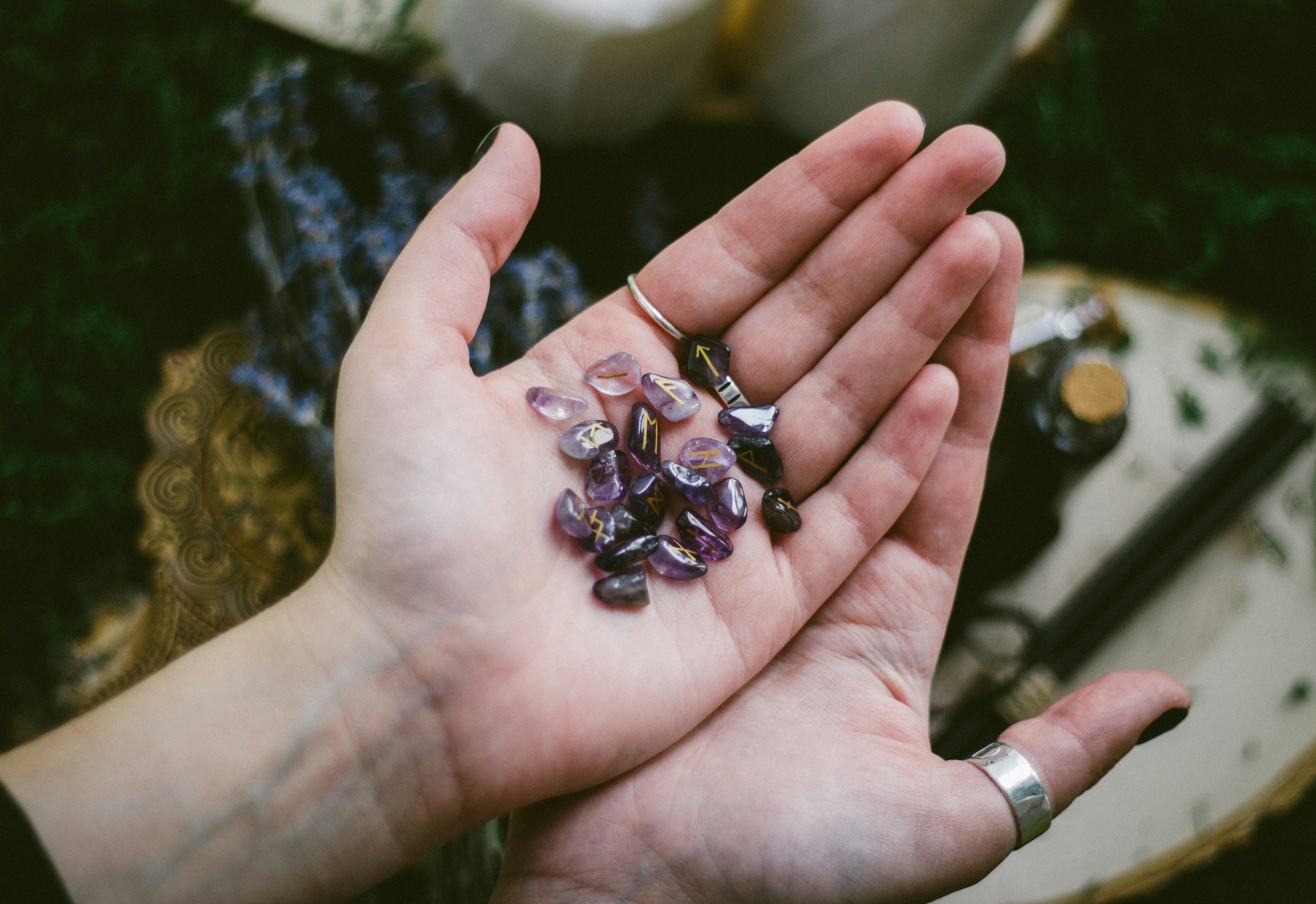 hands holding a set of runes carved in amethyst