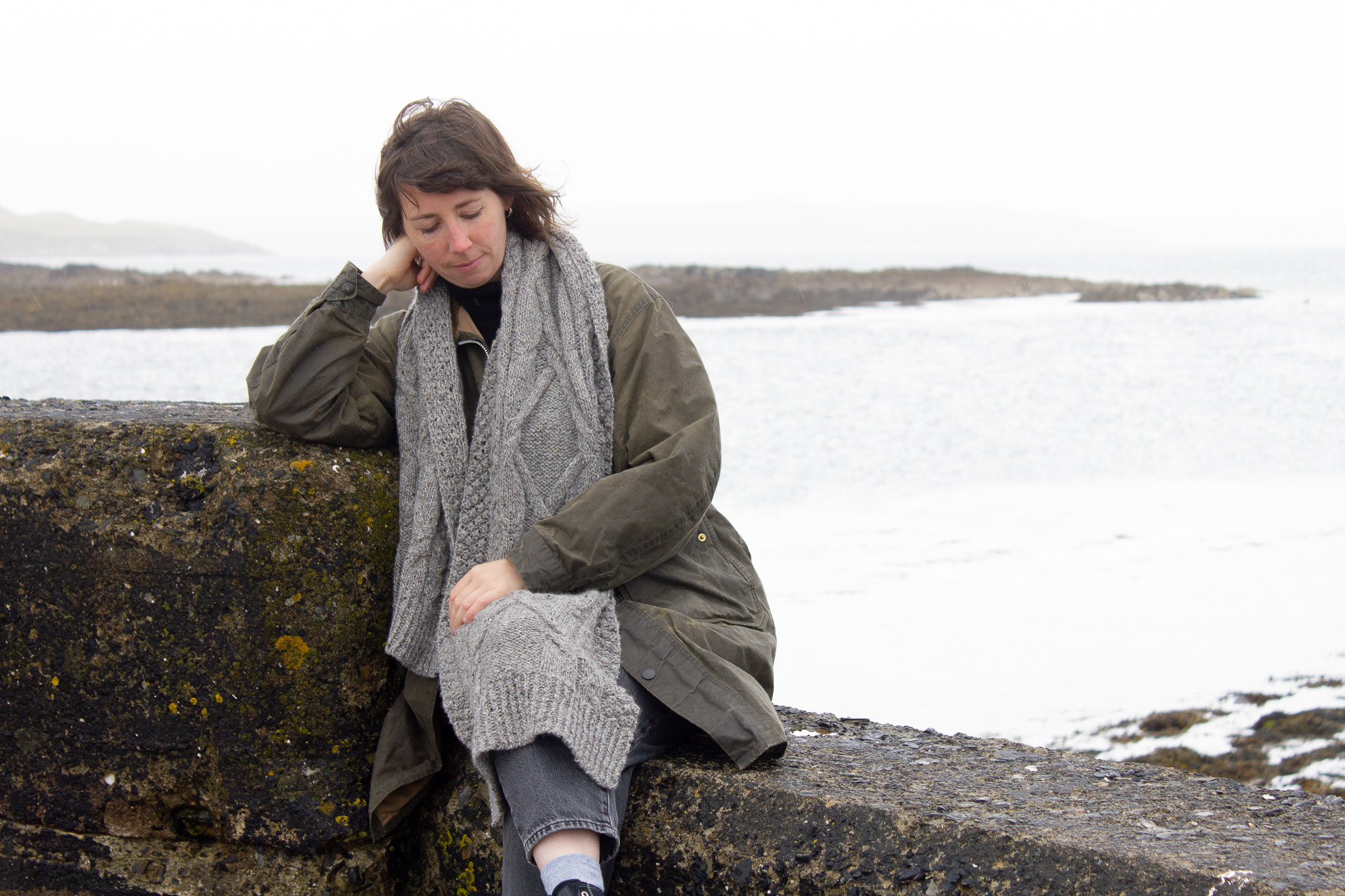 Laura Perrem sitting on a stone wall wearing the Ferry Time wrap.