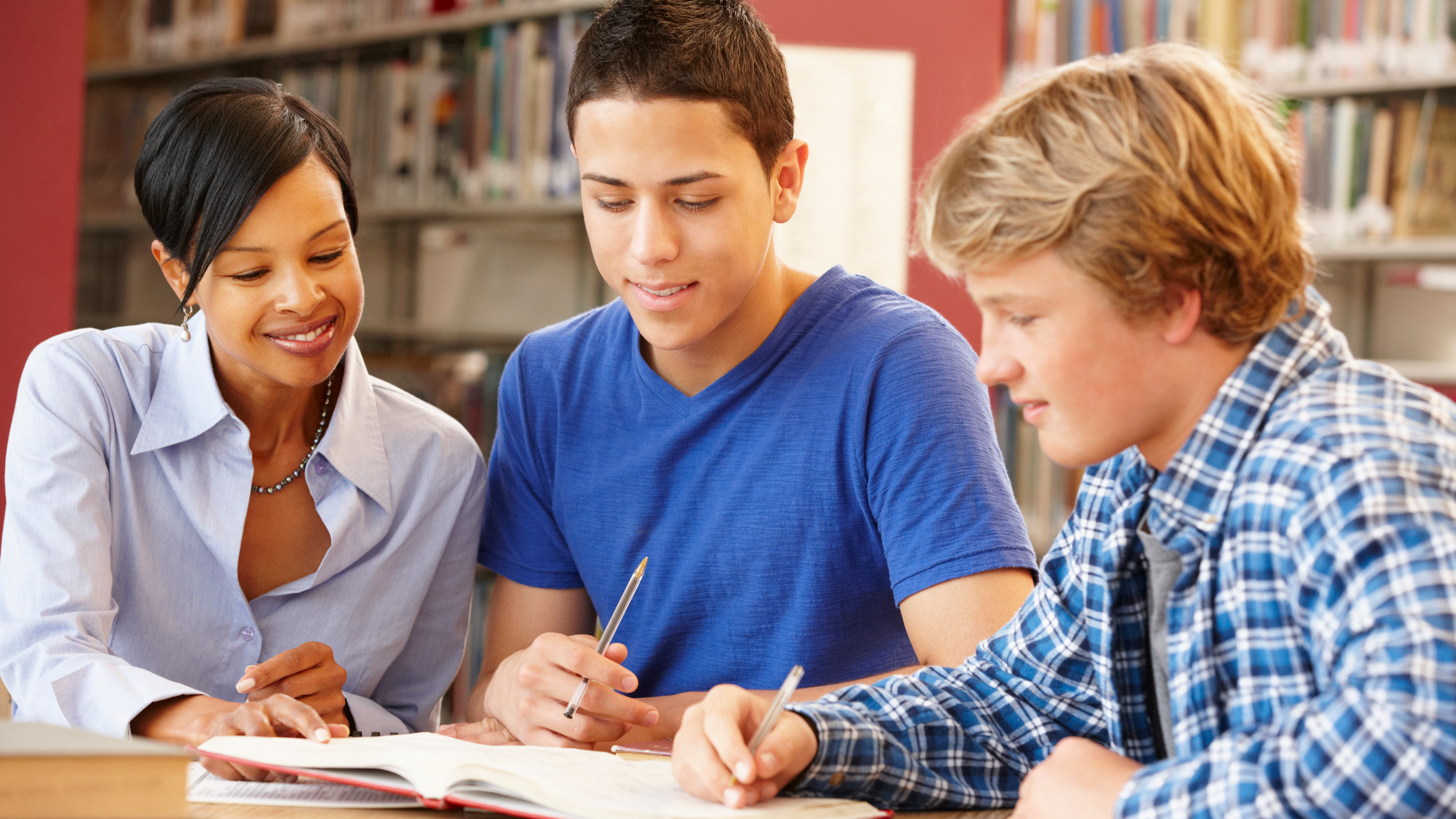 teacher working with two students reading a book