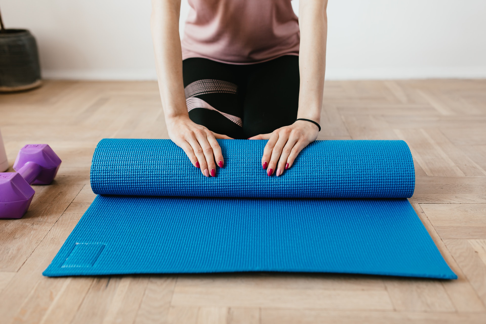 A woman rolls up a yoga mat on the floor