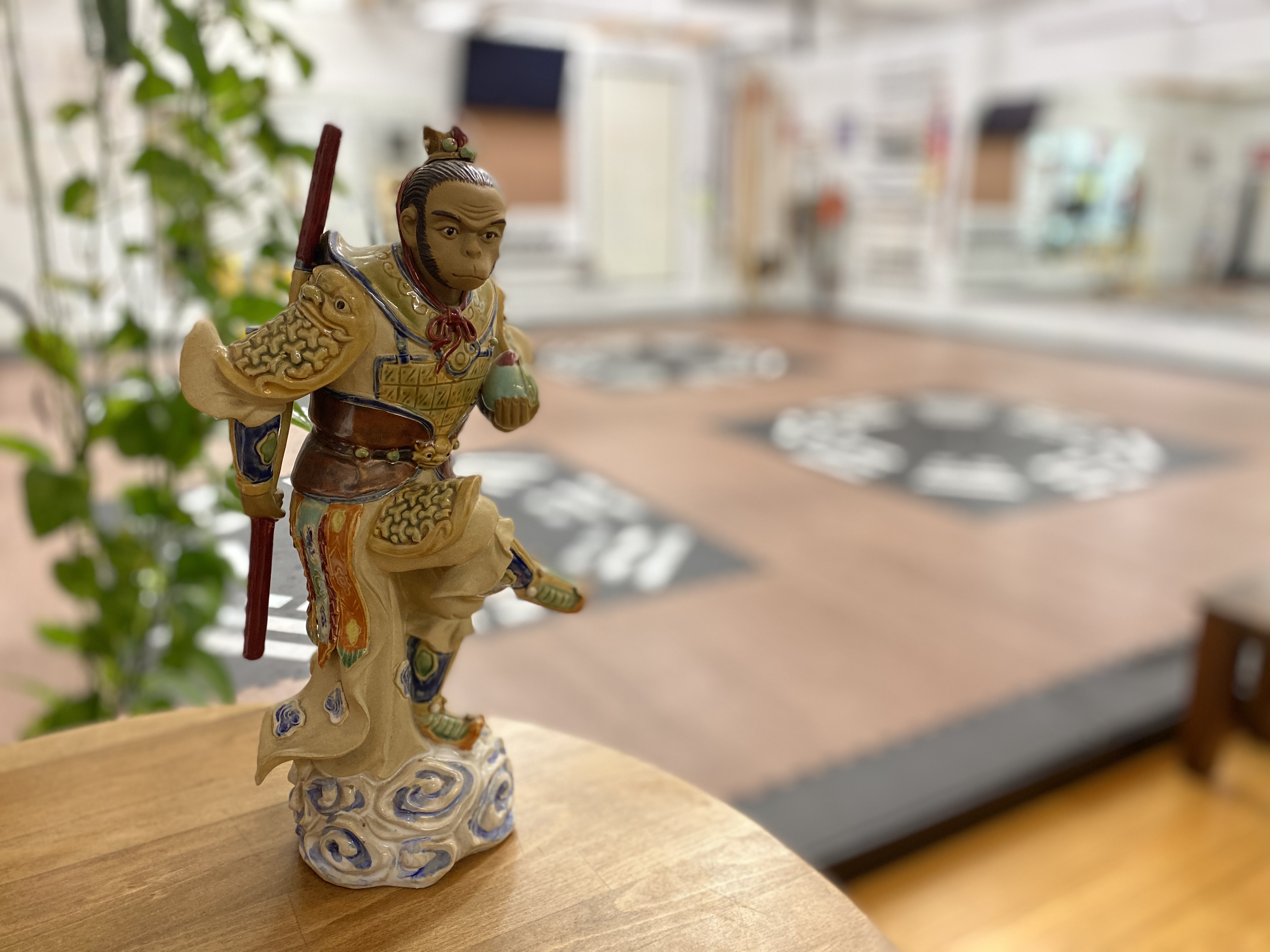 Small and detailed sculpture of the Monkey King in front of an out of focus training space.