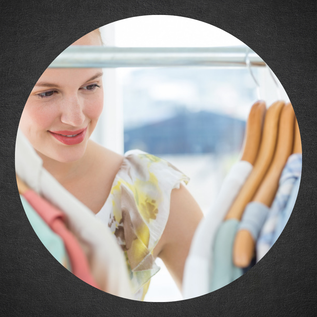 photo of woman smiling in front of rack of hanging clothes