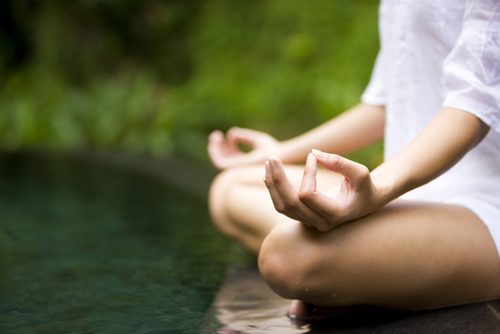 Lotus meditation pose in front of a pond