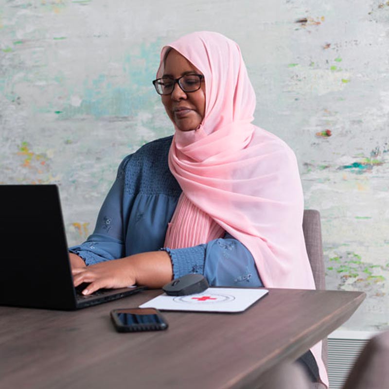 Une personne qui travaille pour la Croix-Rouge canadienne est assise devant un ordinateur de bureau.