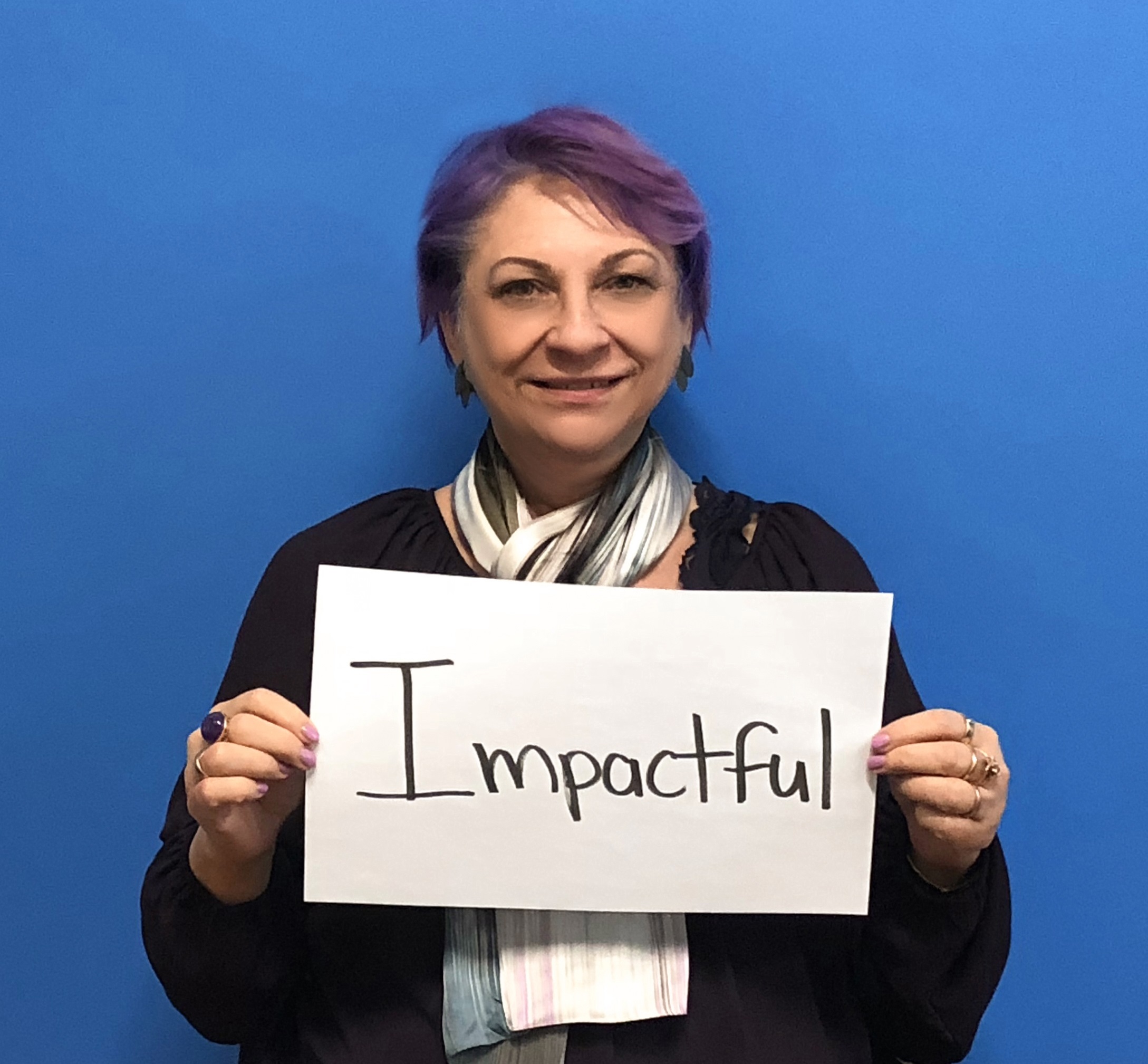 Cheryl Stephens holding a piece of paper with the word &quot;impactful&quot; on it