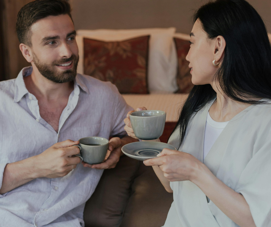 Asian woman and white man drinking tea at foot of bed