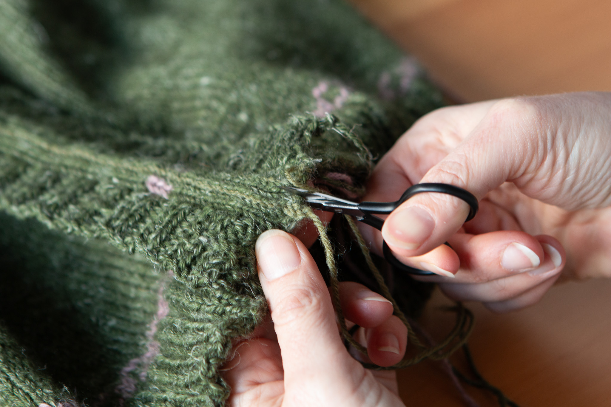 Close up of scissors cutting the Daigean Cardigan. 