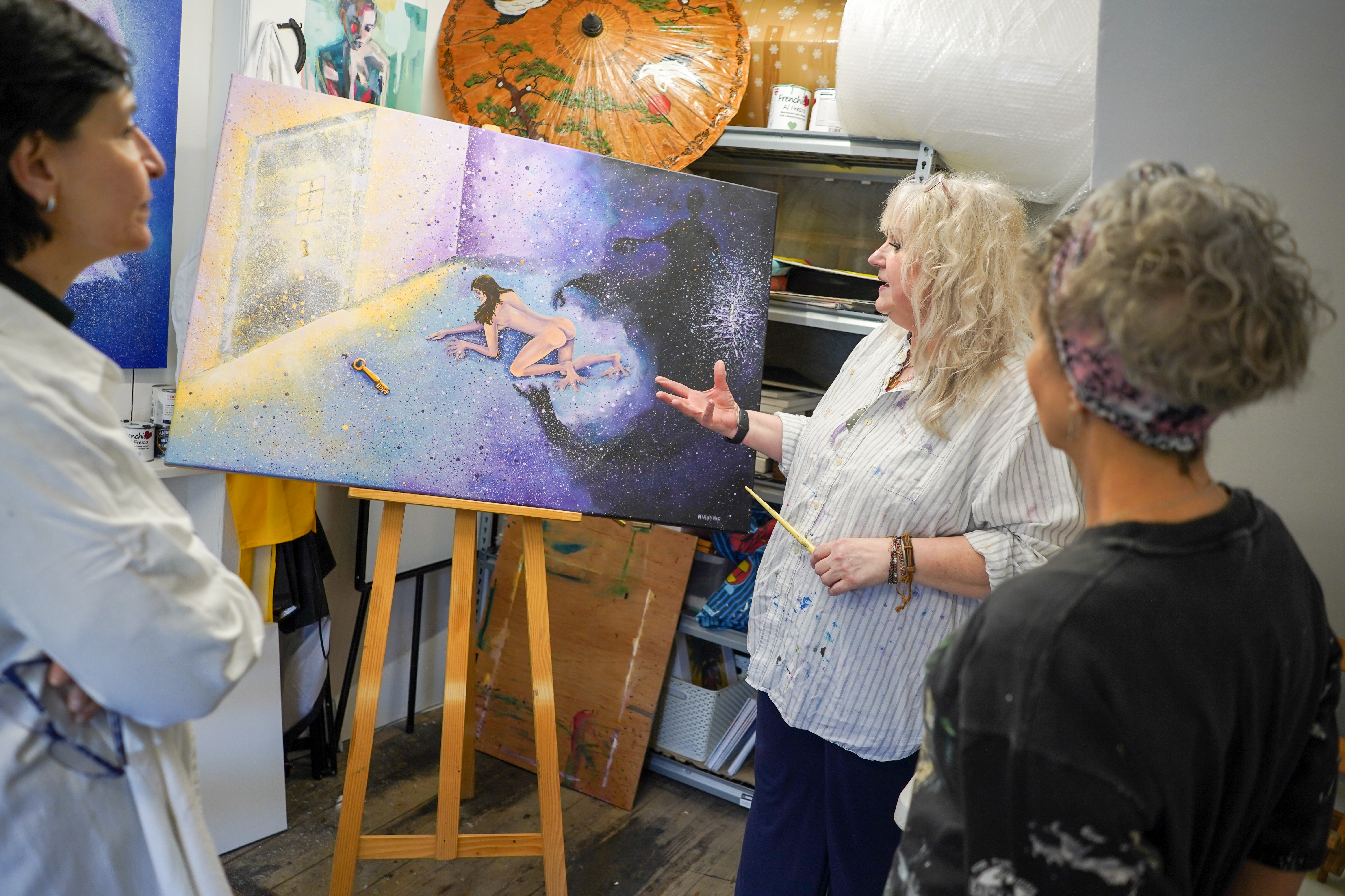 Picture of a woman teaching 2 artists