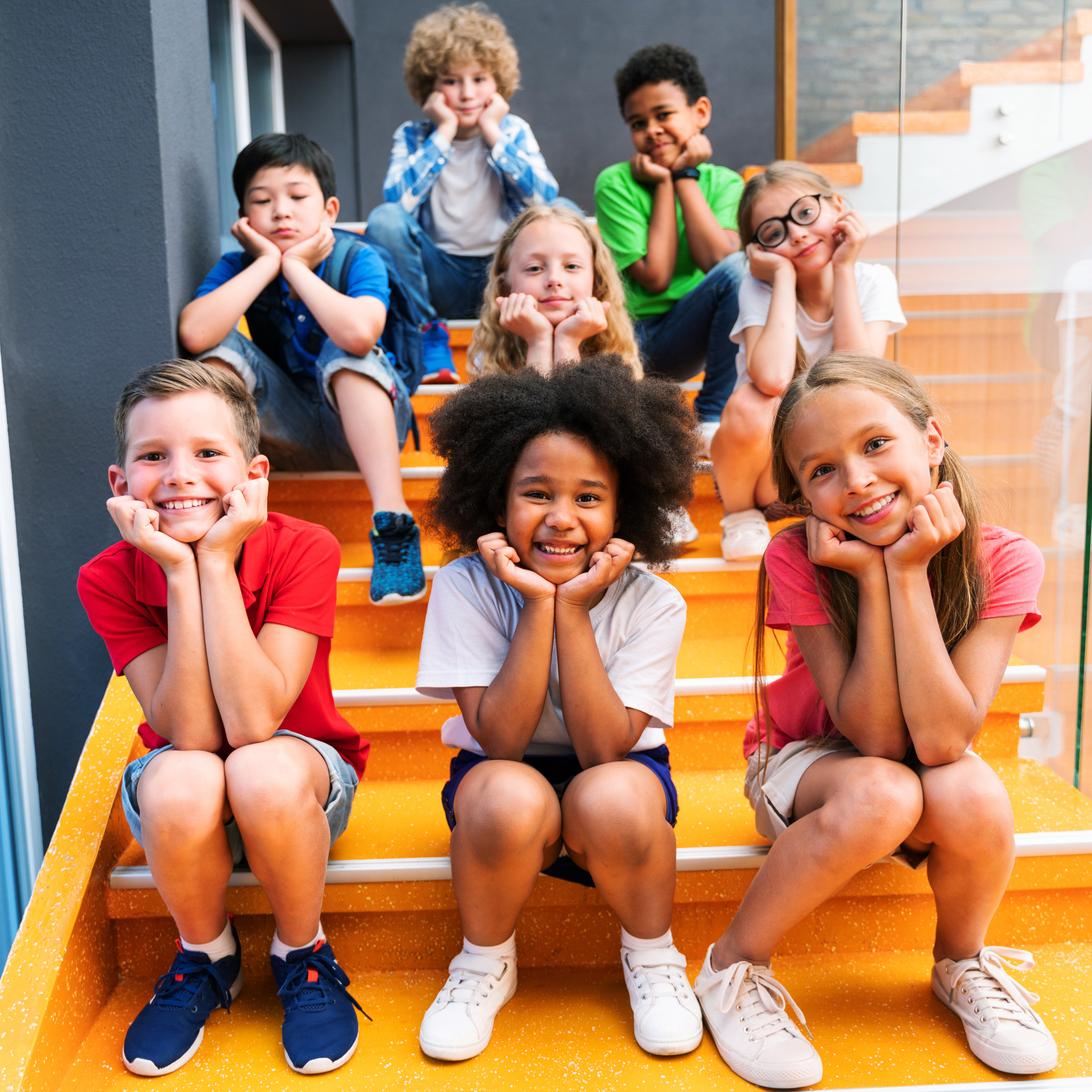 smiling kids sitting on steps with chins in their hands