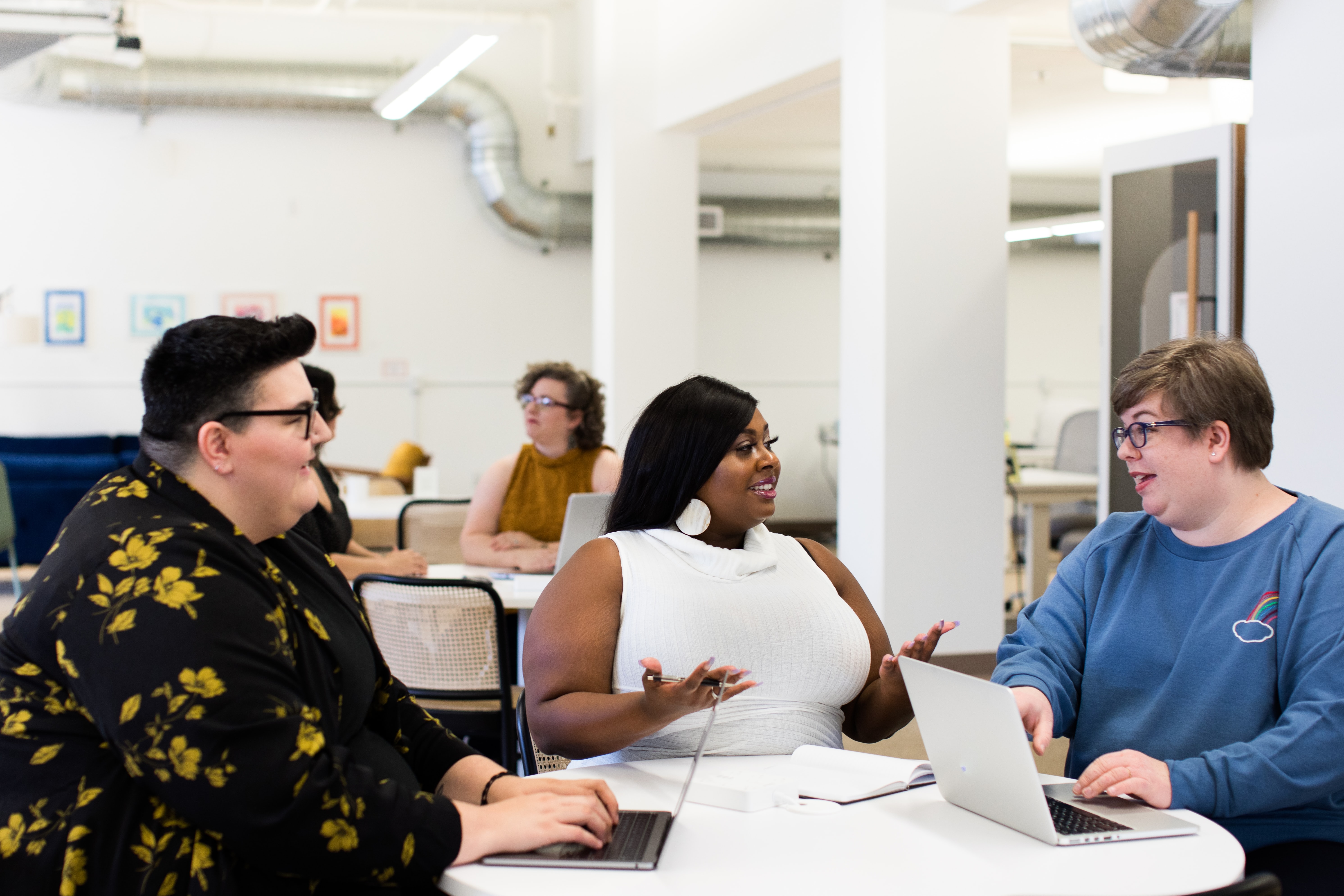 Three people talking while one woman types at a computer