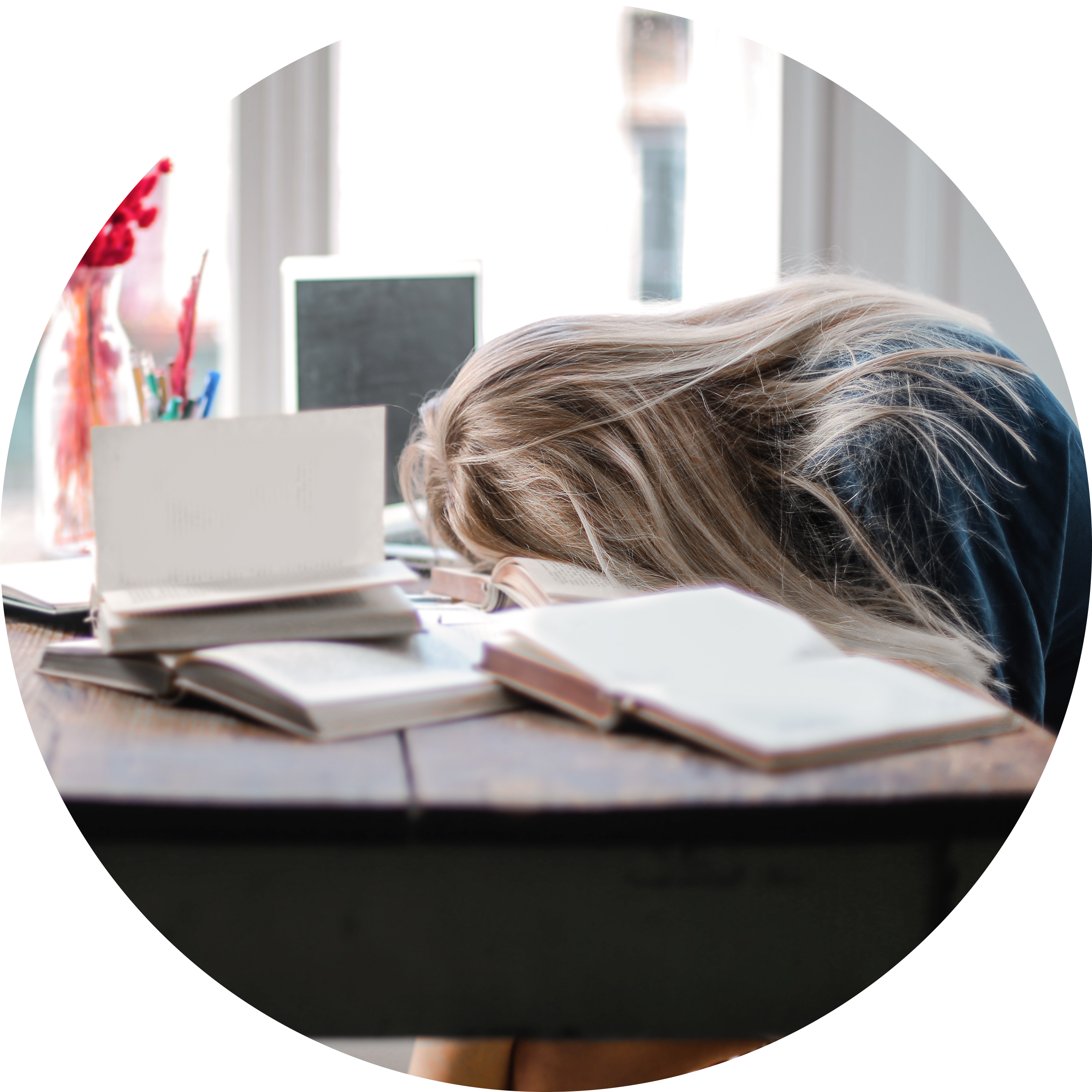 A girl with her head down on her desk, depressed by her poor mental health. She needs the courses and coaching Psycophi has to offer!