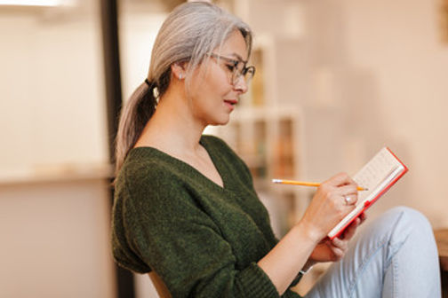 A middle-aged woman writing in a notebook.