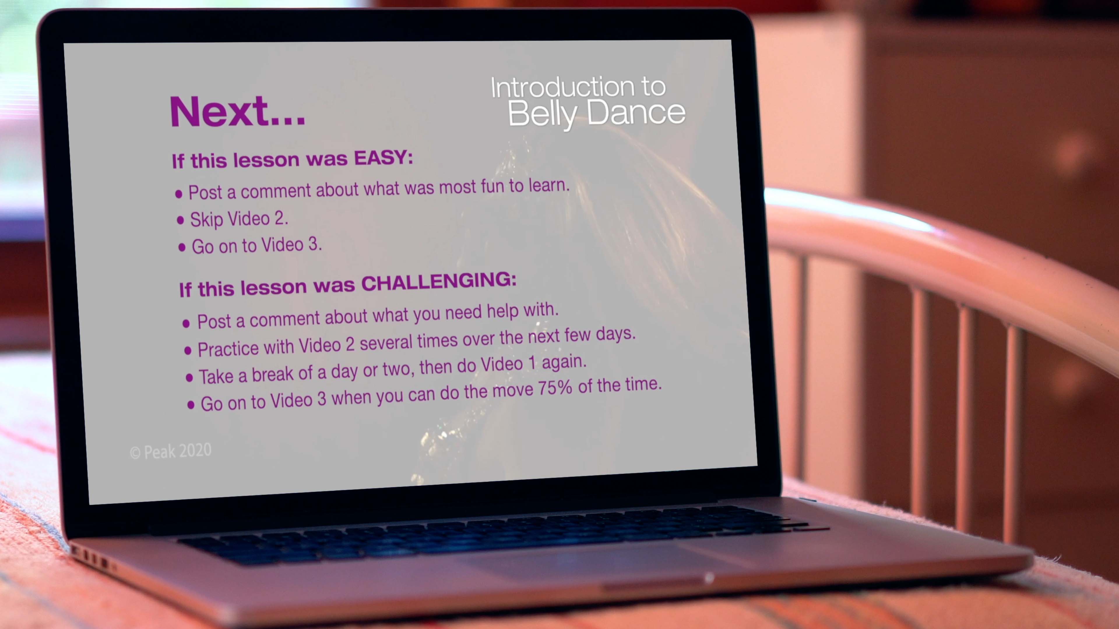 laptop computer on bed showing online belly dance course on screen