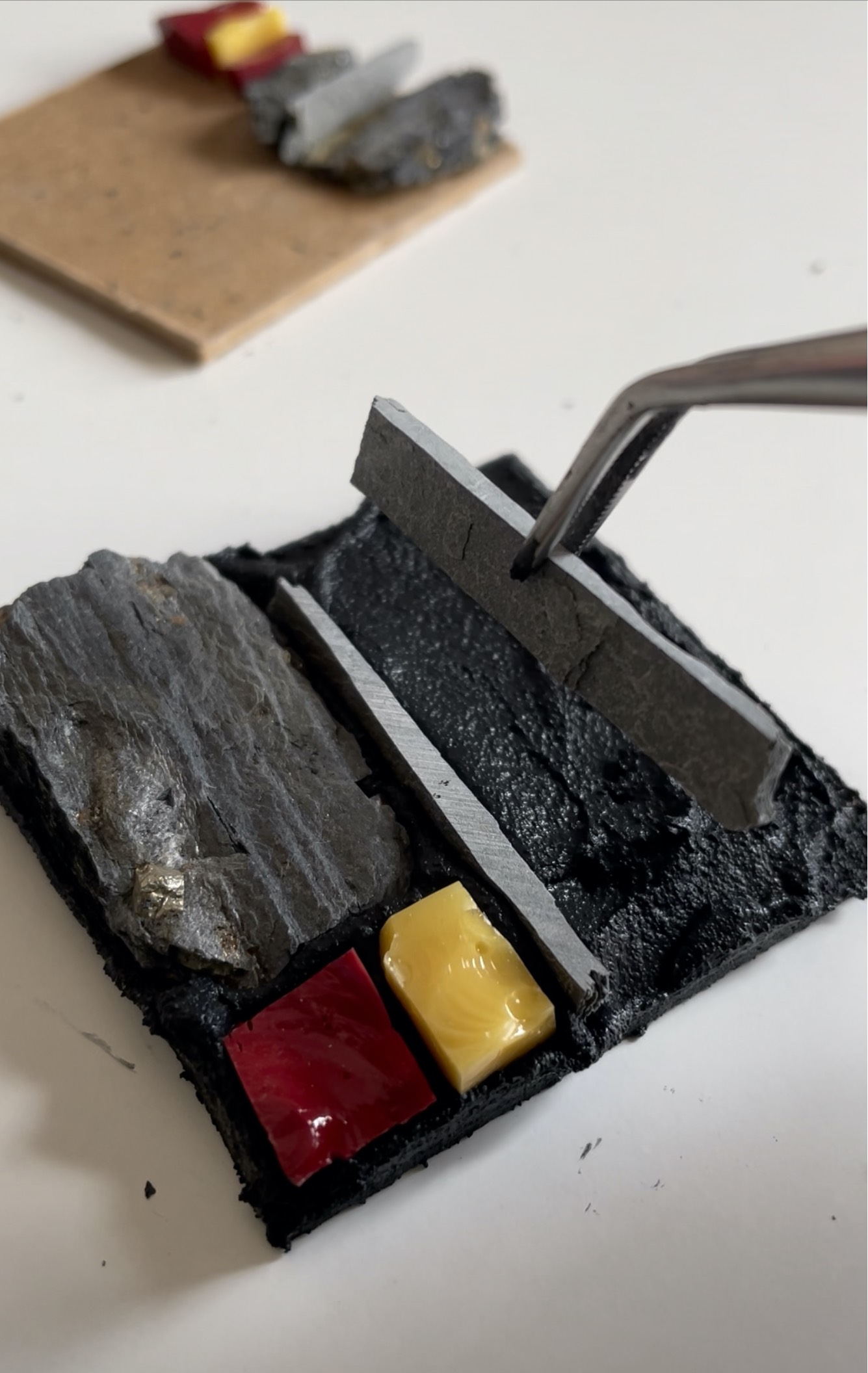 a pair of tweezers holding a piece of slate ready to place it into a mosaic