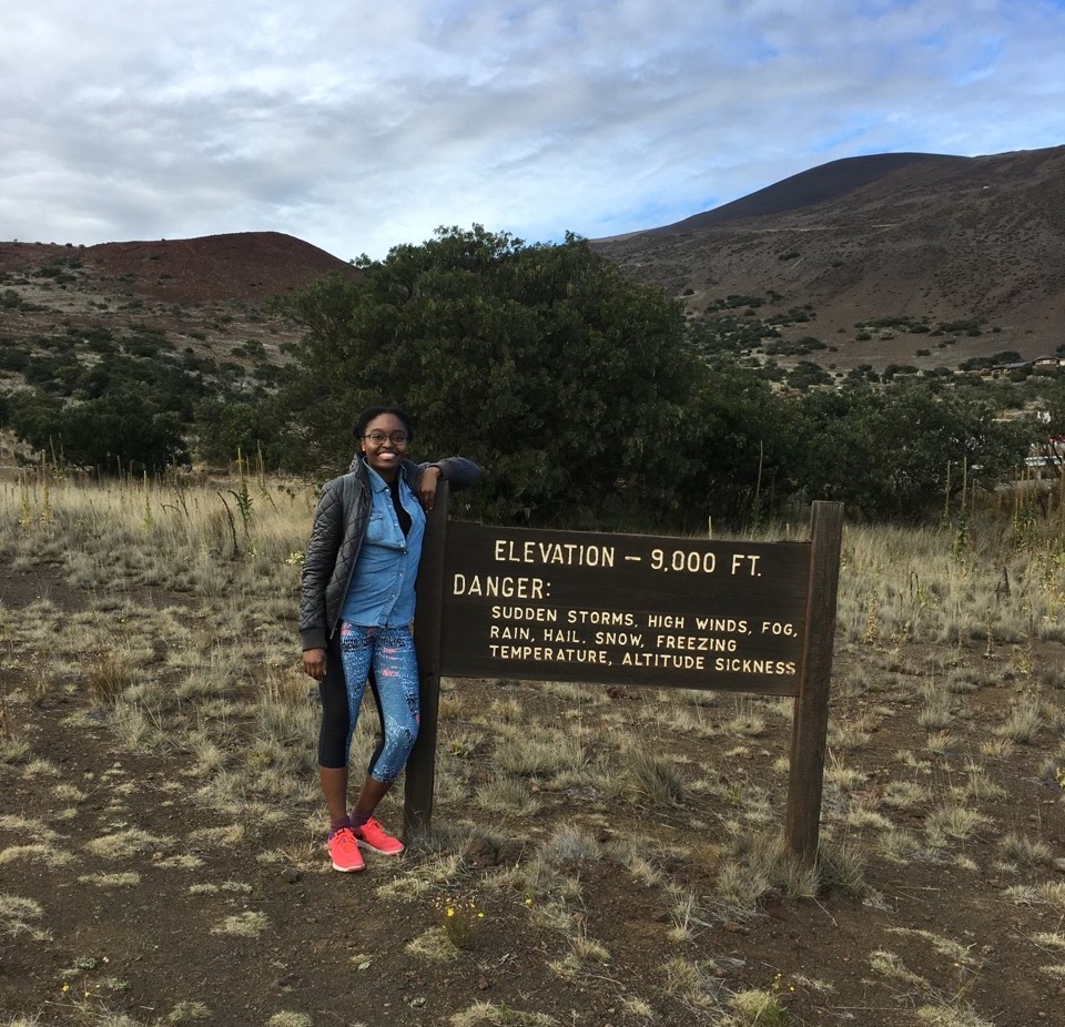 Outdoor 101 student standing in front of a trail sign on a mountain