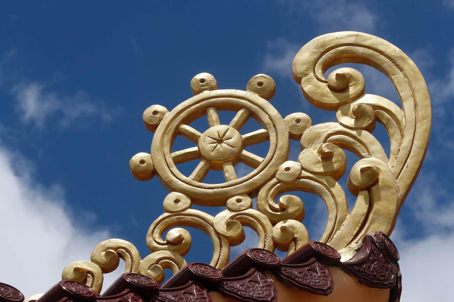 Golden painted Dhamma Wheel set against the sky