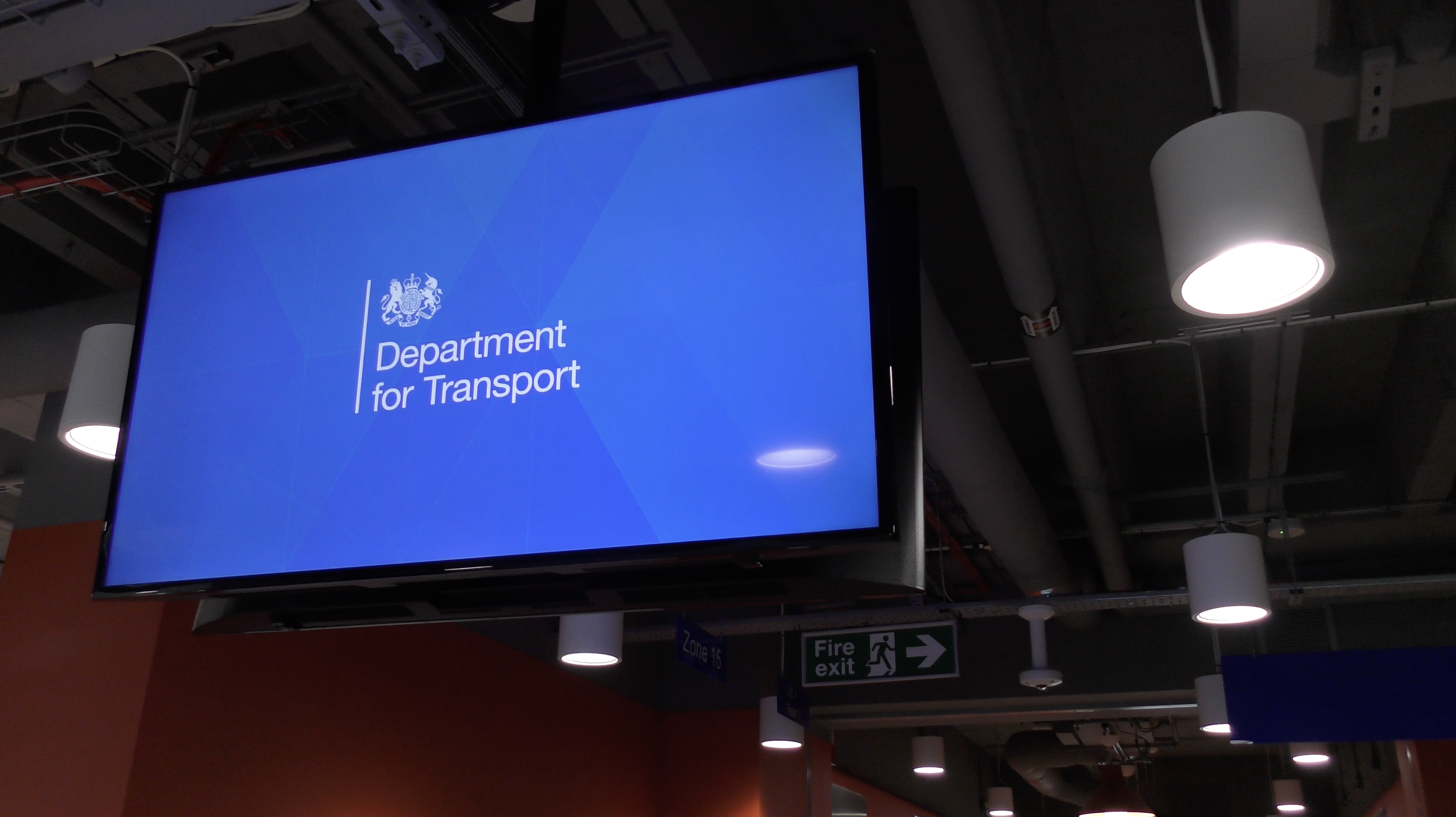 Television screen showing the Department for Transport Logo in a large room