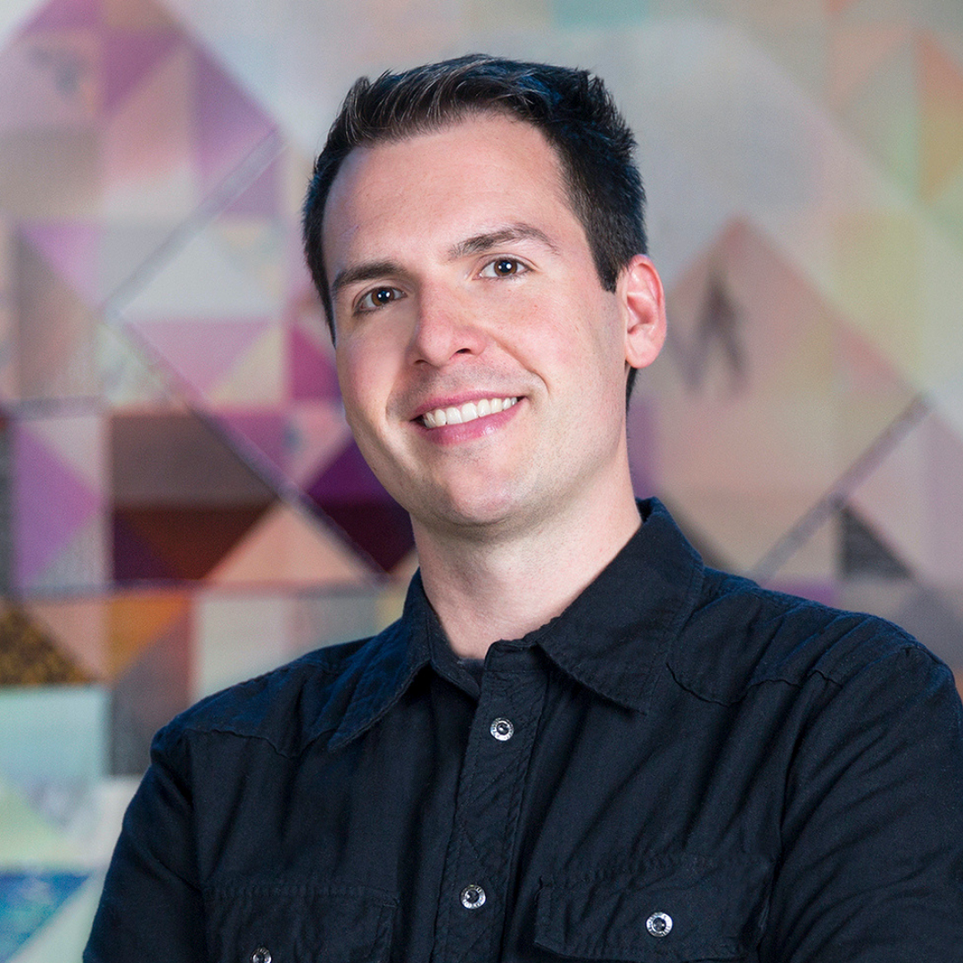 Dave Csinos in a navy shirt in front of a multicolored background