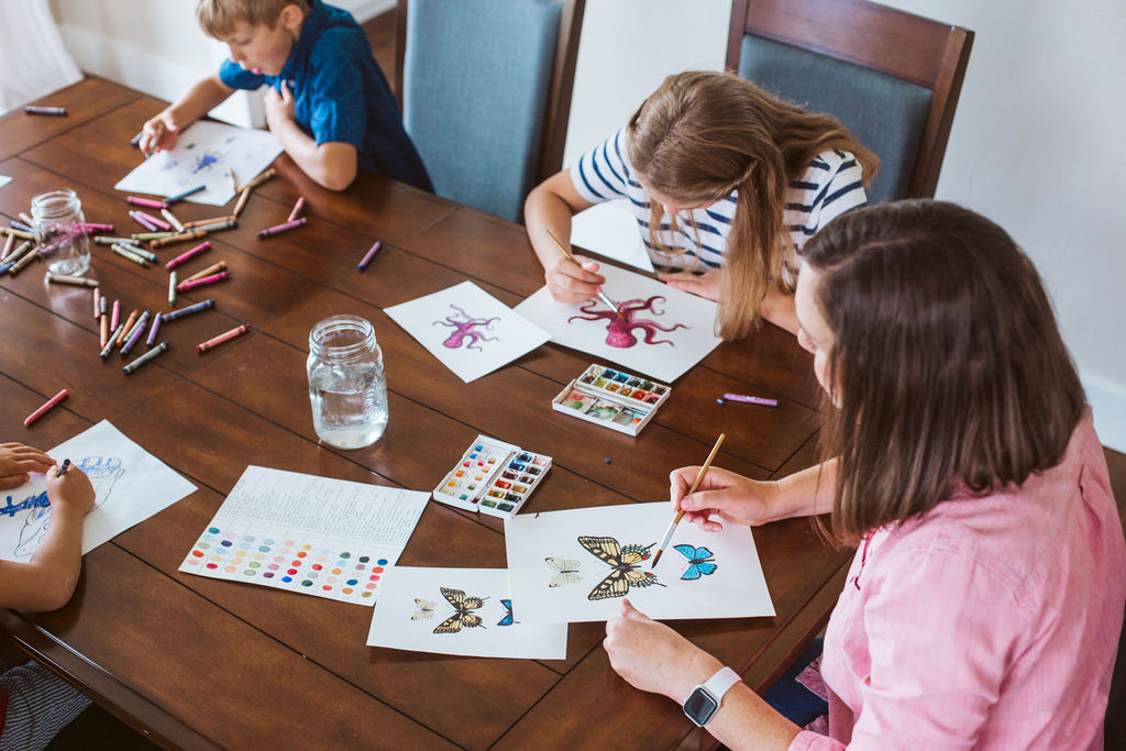 Mother and children sitting at kitchen table coloring and watercolor painting nature images