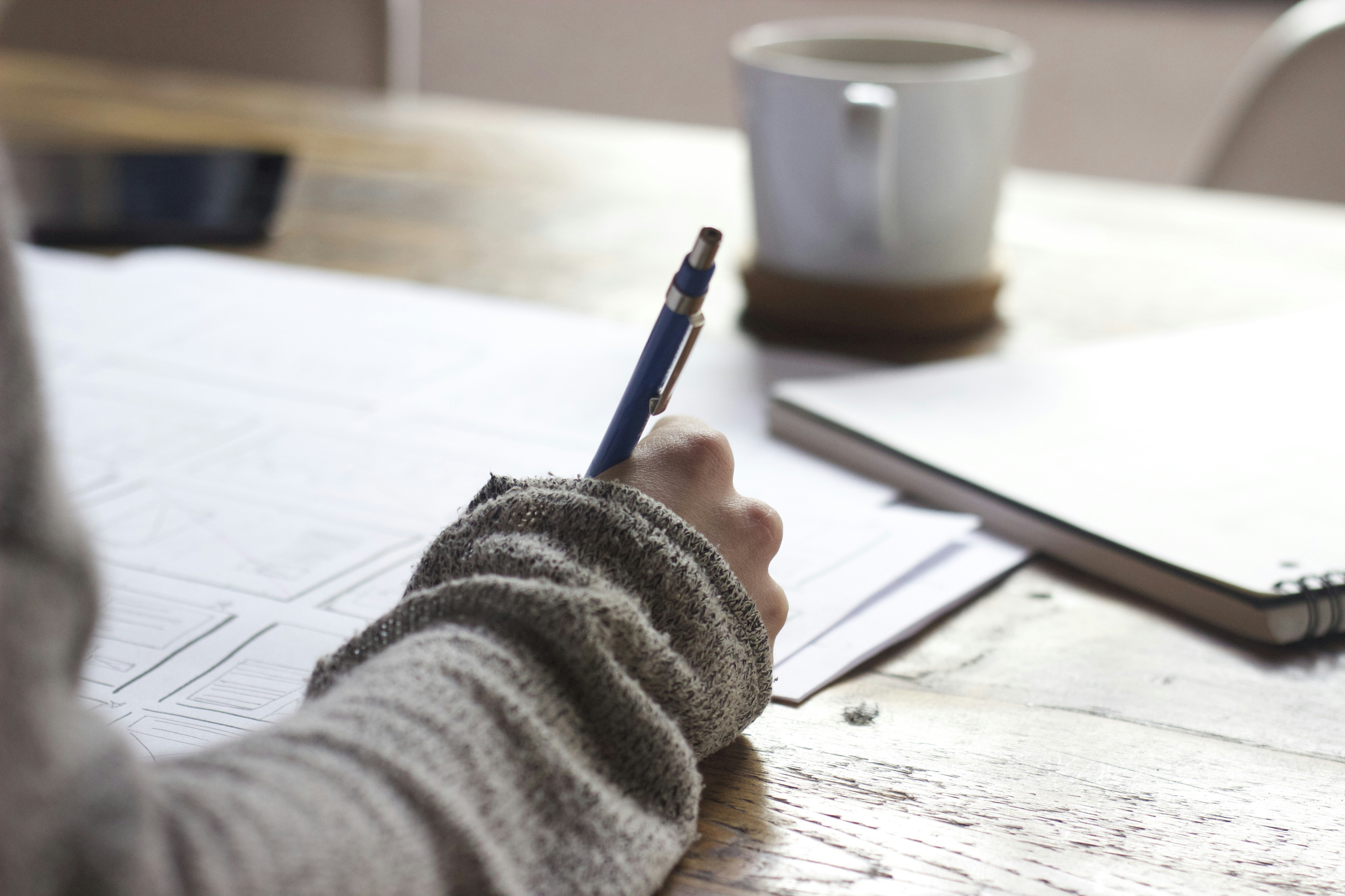 Woman writing with pen at a home desk.