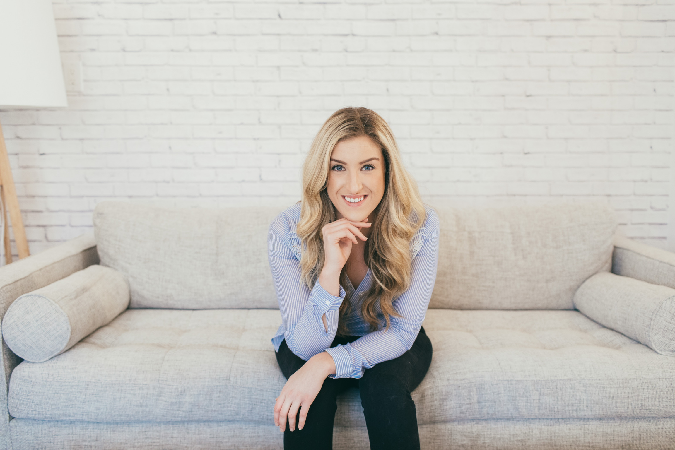 Photo of Meg Gaic, founder of Get Glow sitting on couch smiling at camera