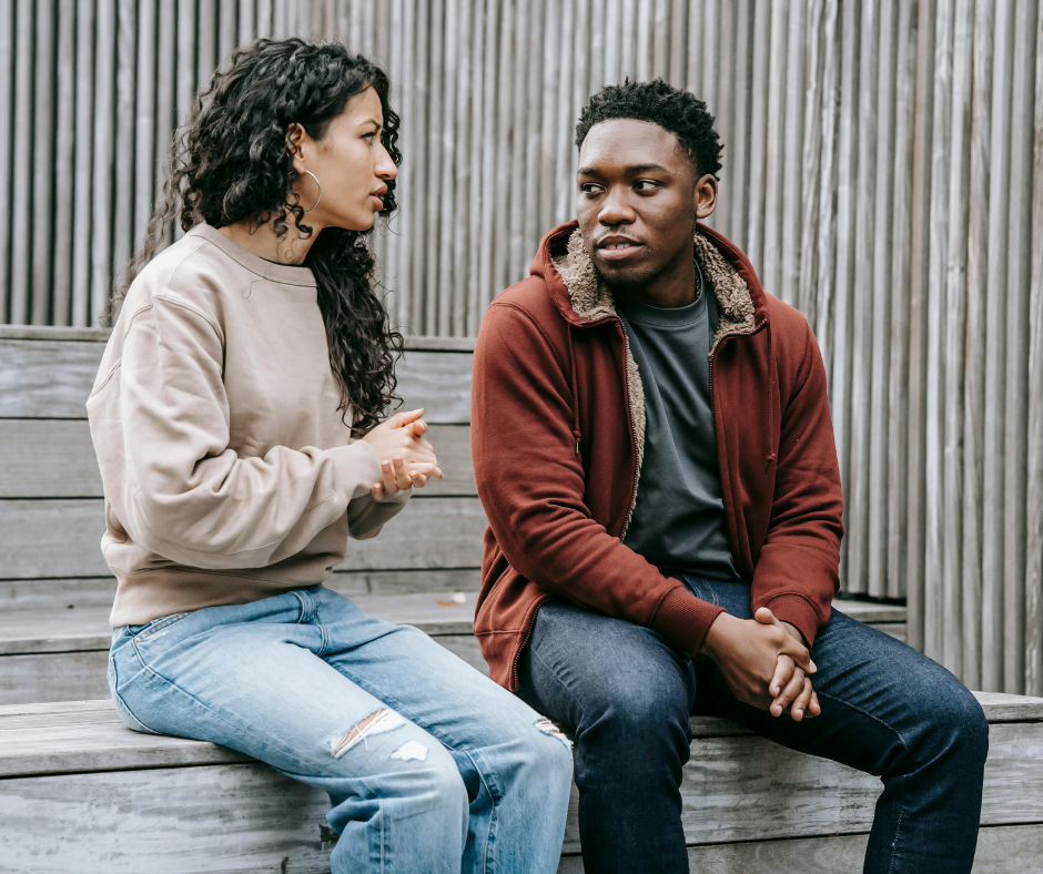 brown skinned couple talking while sitting on steps