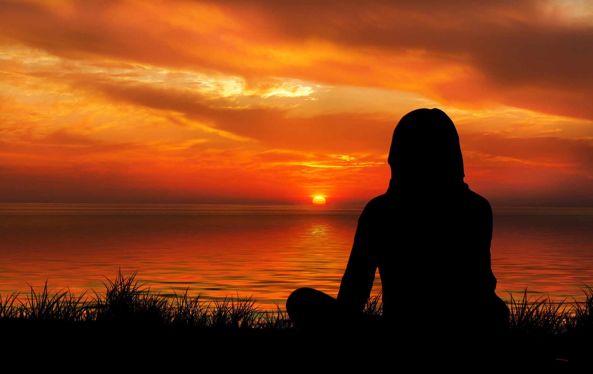 Woman looking at sunset on the sea and embracing change