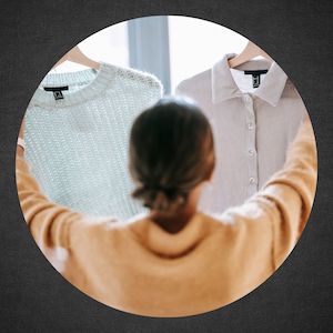 woman holding up two different shirts on hangers